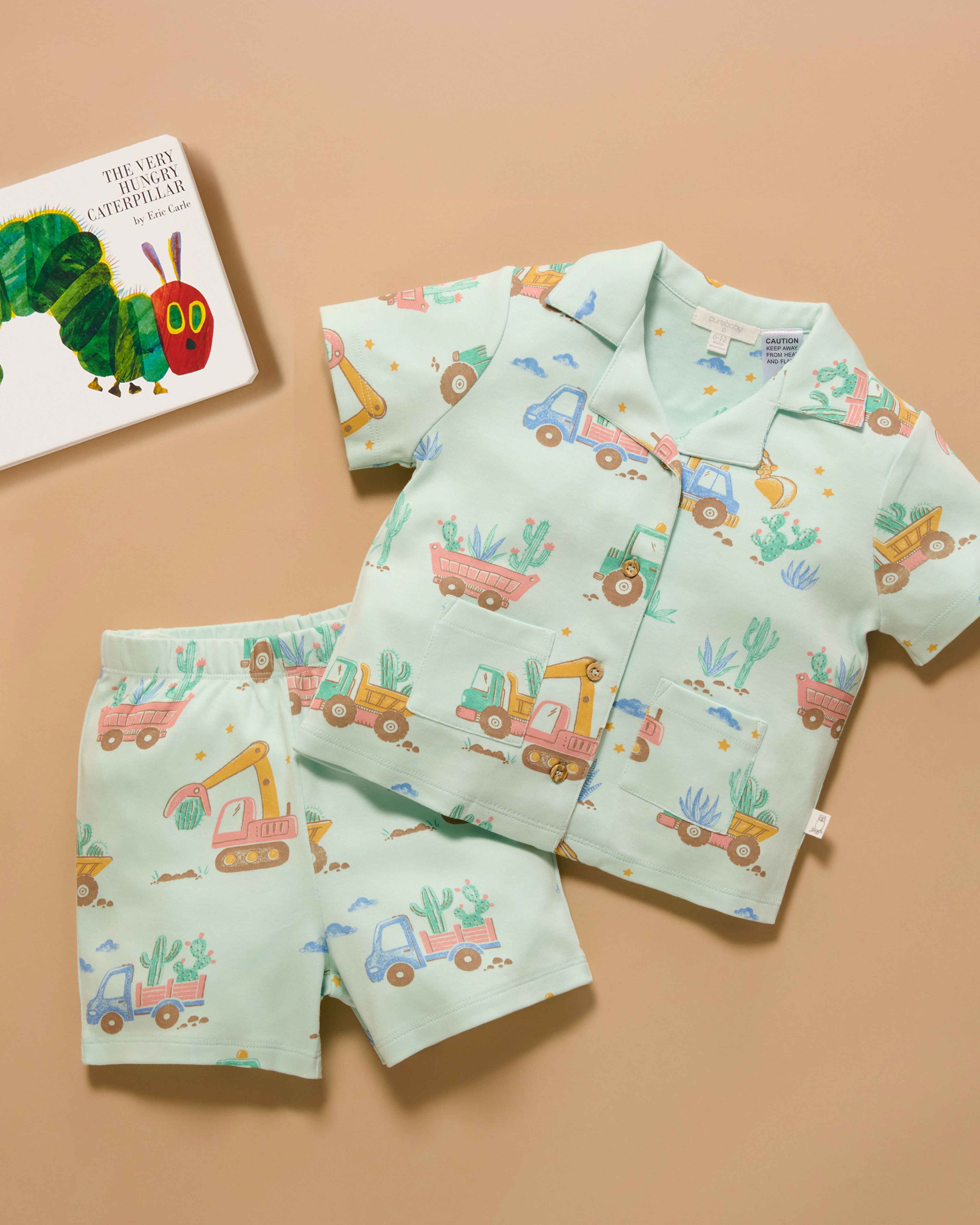 Flatlay of green button up pyjamas with truck print all over