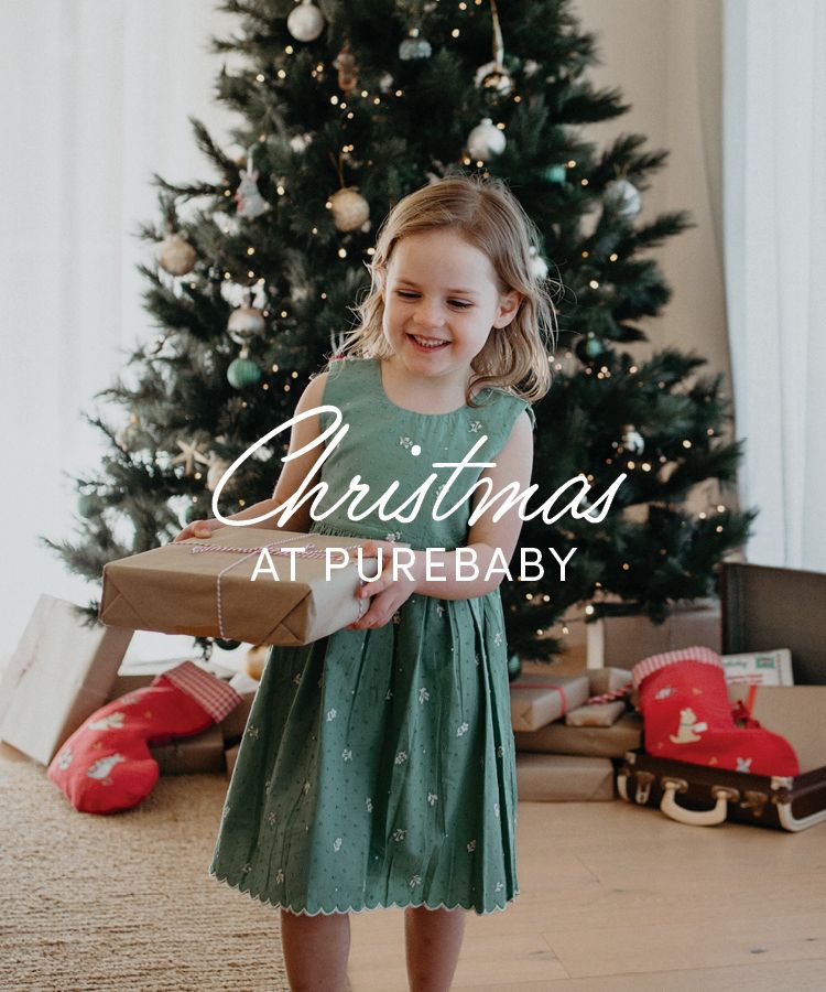 child wearing a kids Christmas dress holding a present