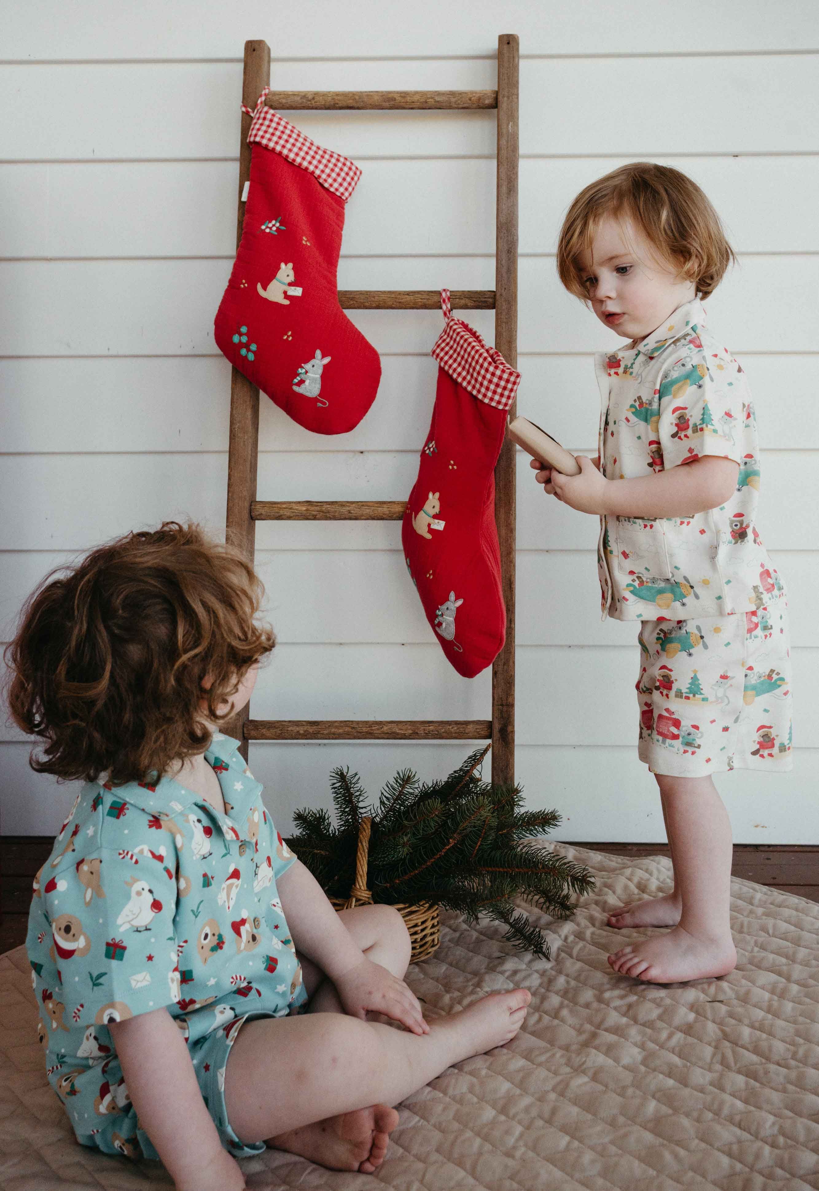 Siblings in matching Purebaby Christmas pyjamas opening presents on Christmas morning.