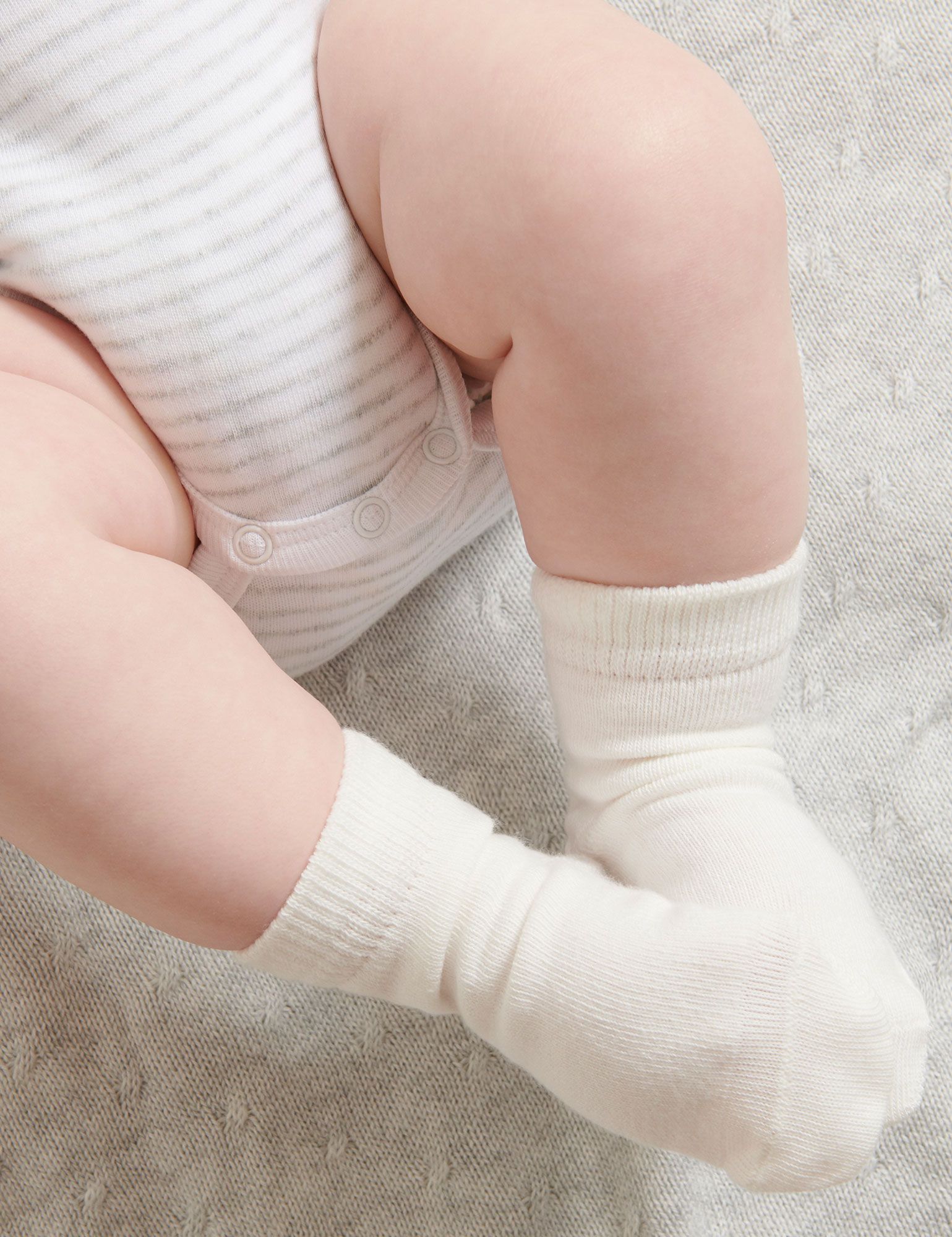 Baby wearing Purebaby 3 Pack Socks in soft neutral tones