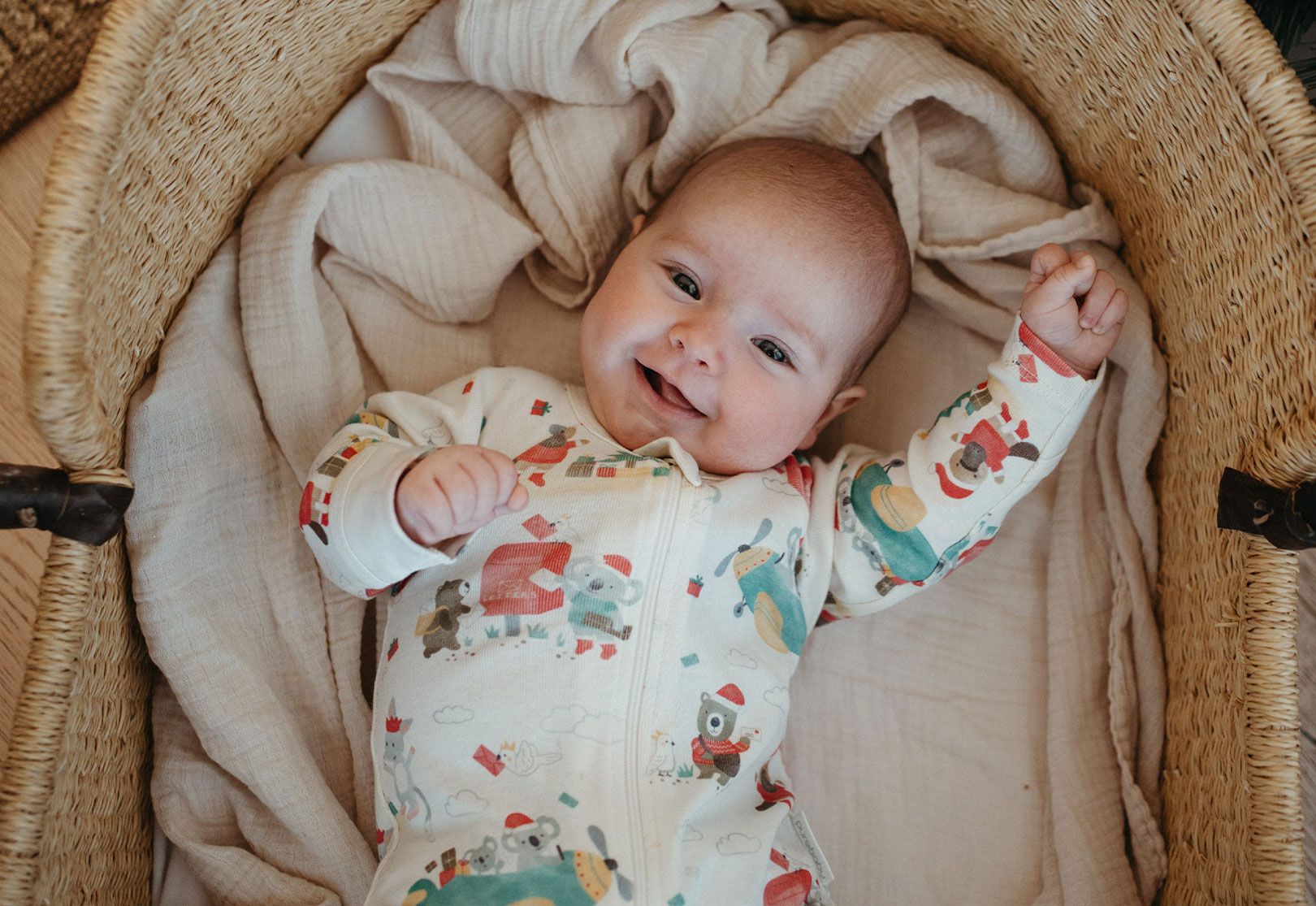 Baby laying in bassinet wearing Purebaby Christmas Growsuit