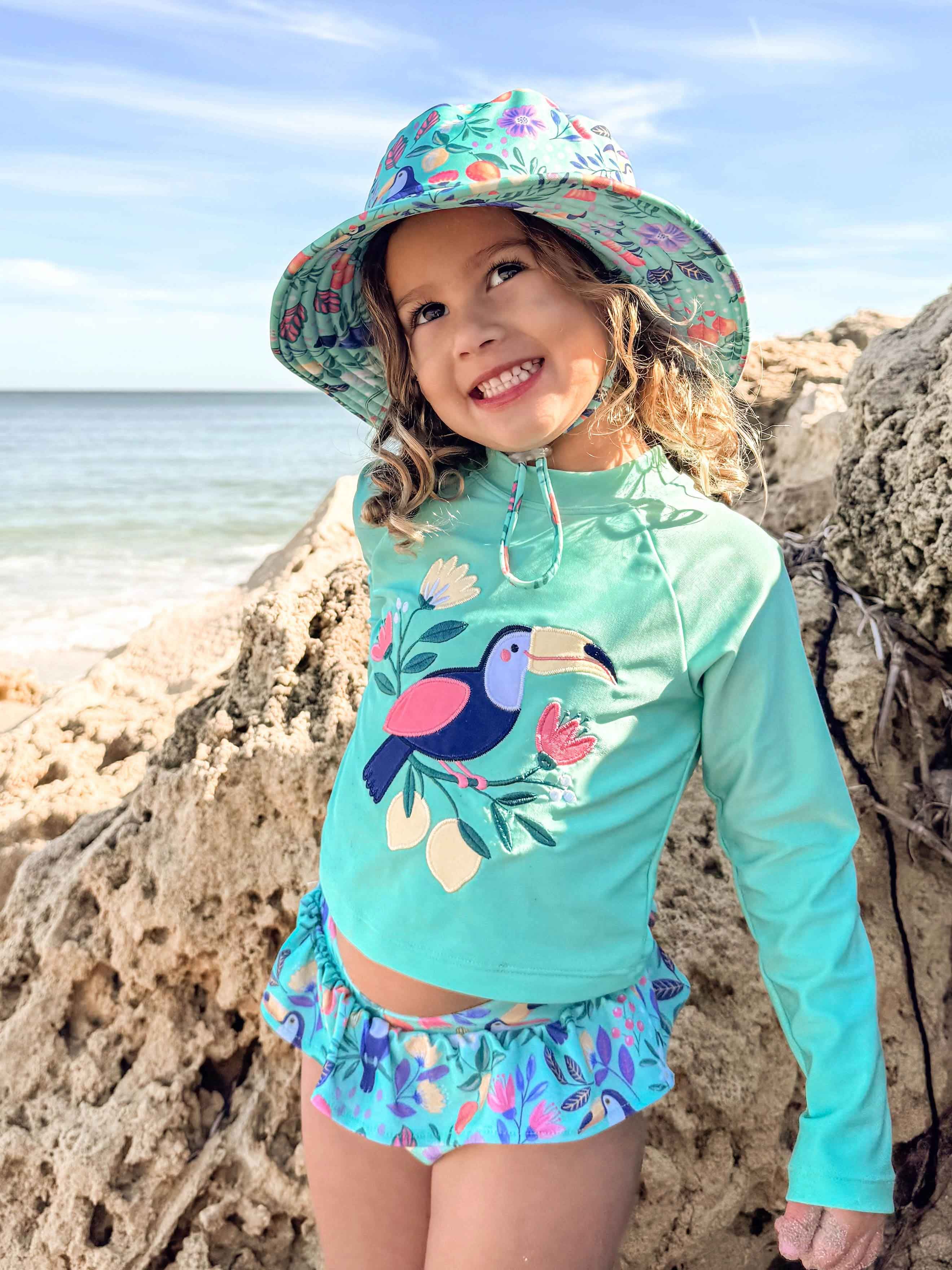 Child playing at the beach in Purebaby's Toucan Long Sleeve Rashie Set