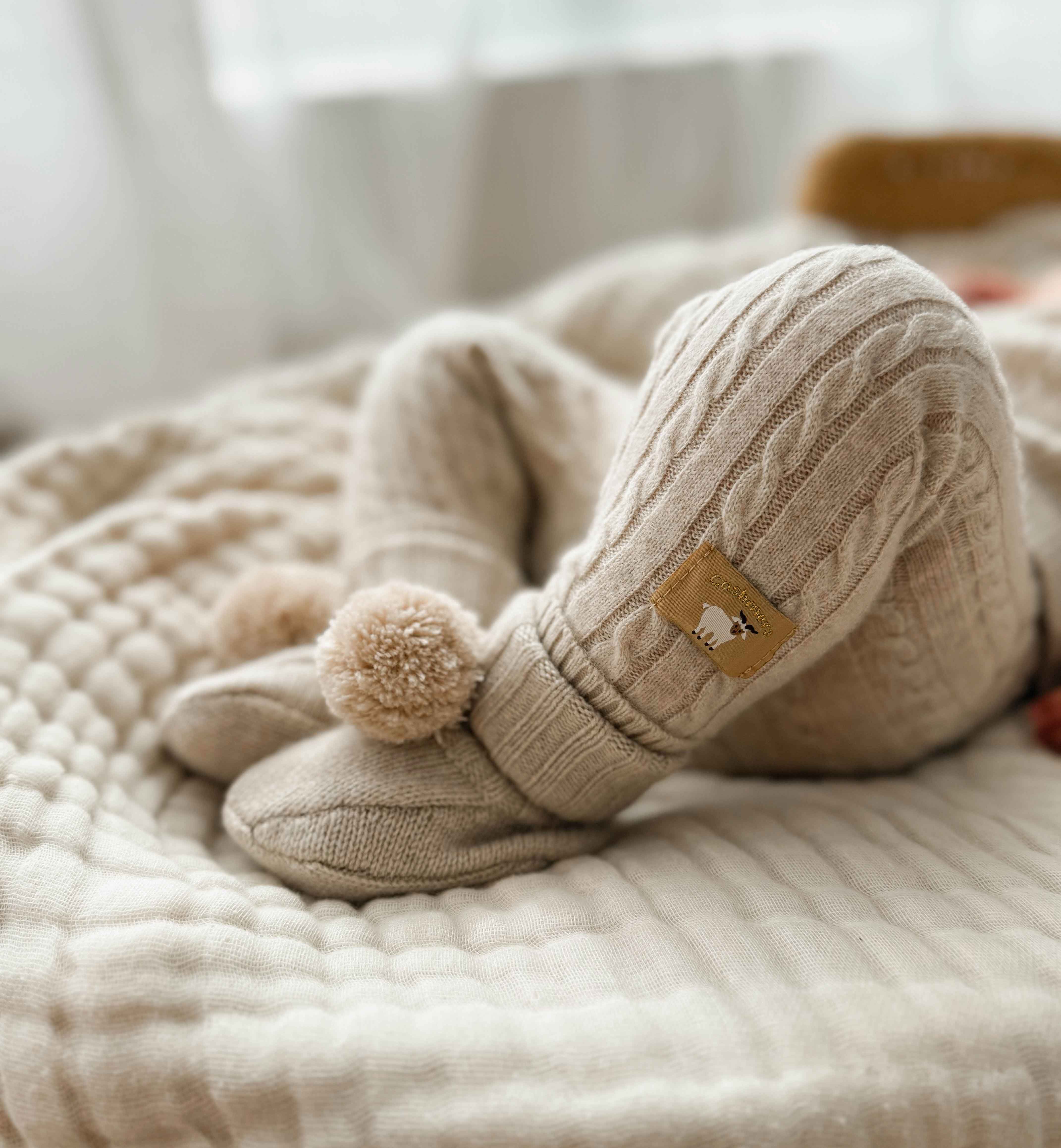 Laying baby wearing cashmere booties and leggings