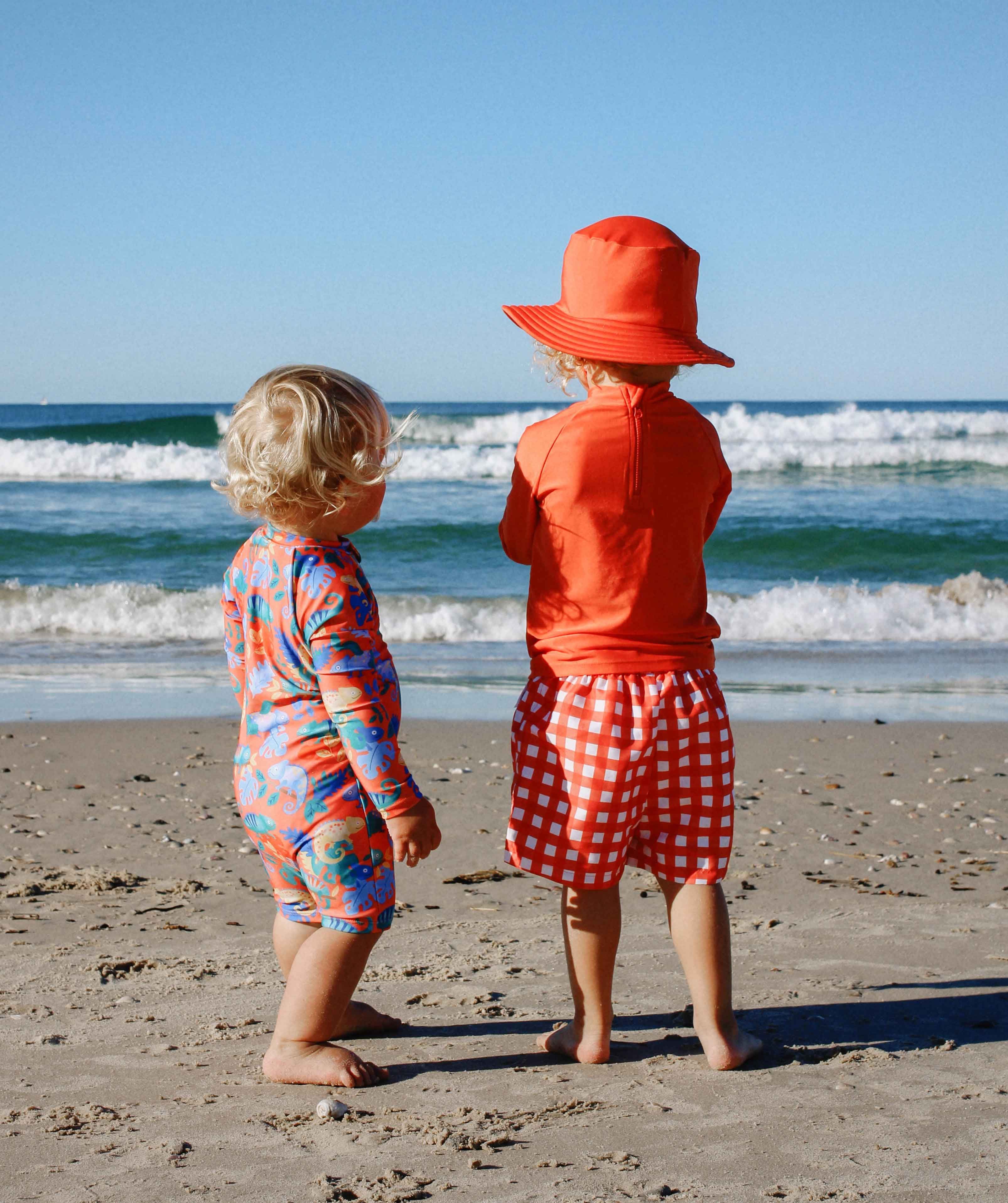 2 boys at the beach wearing orange Purebaby swimwear 