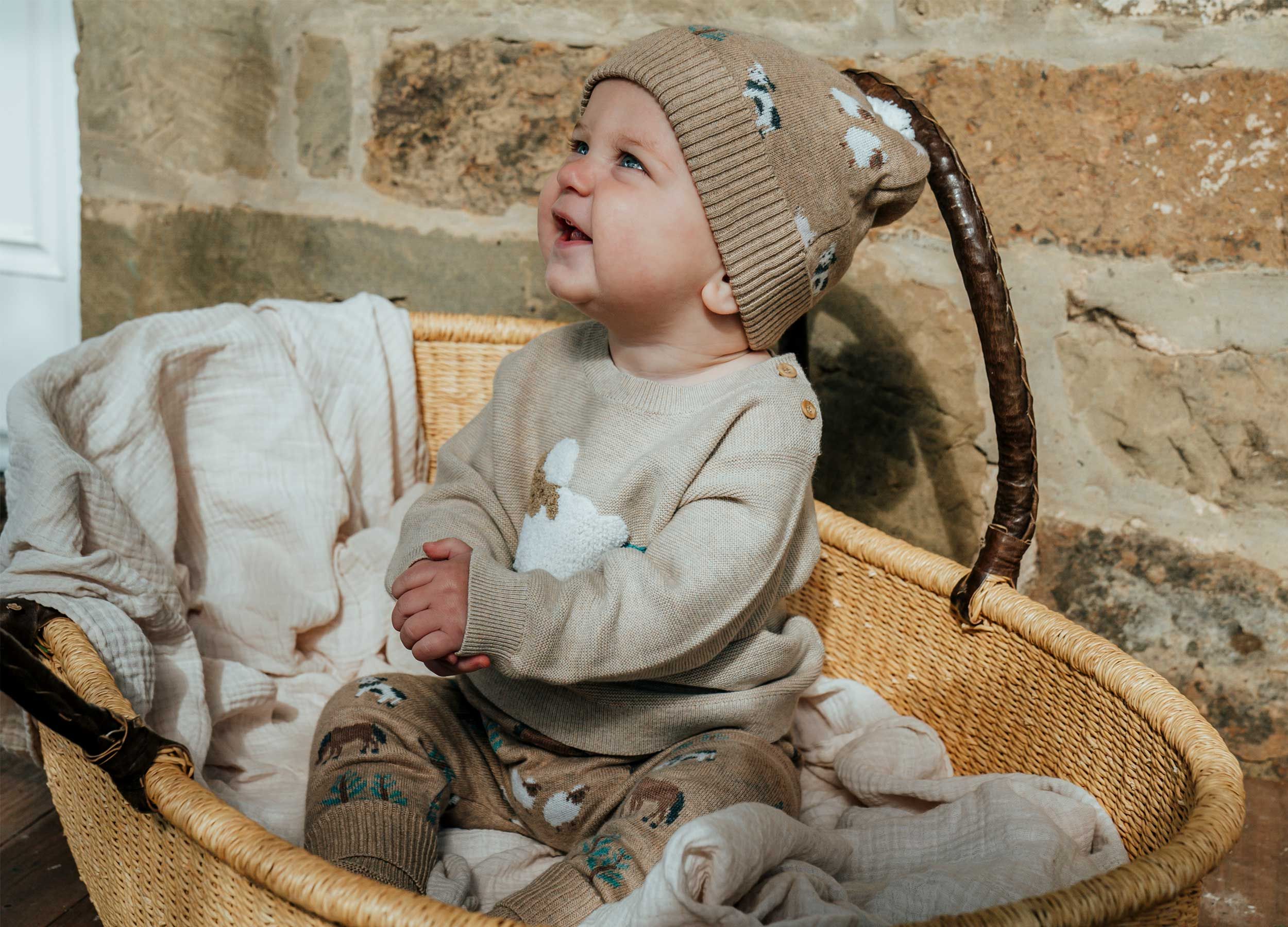 Baby wearing knitted neutral beanie, jumper and leggings