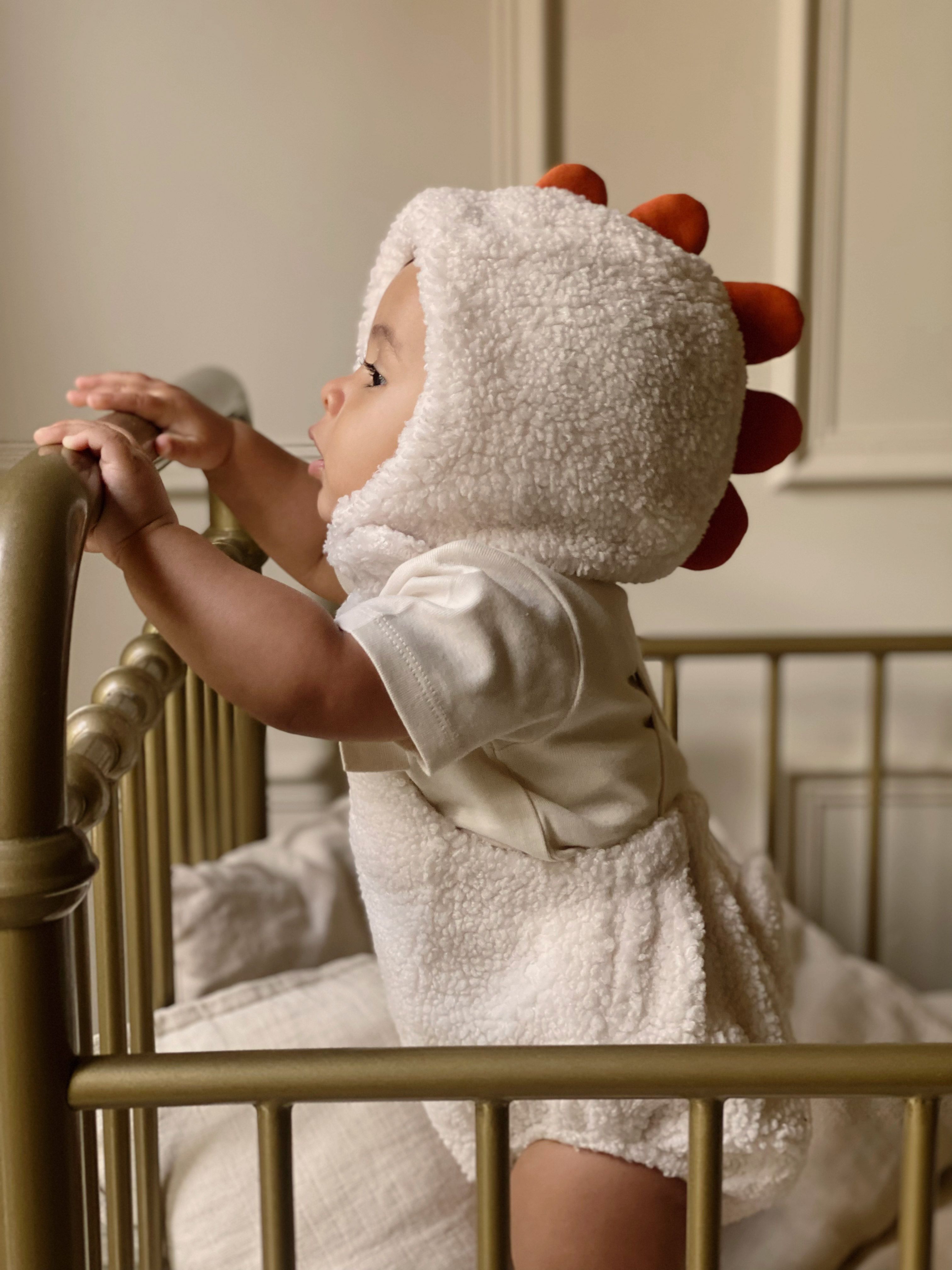 Baby in cot, standing up wearing Easter outfit