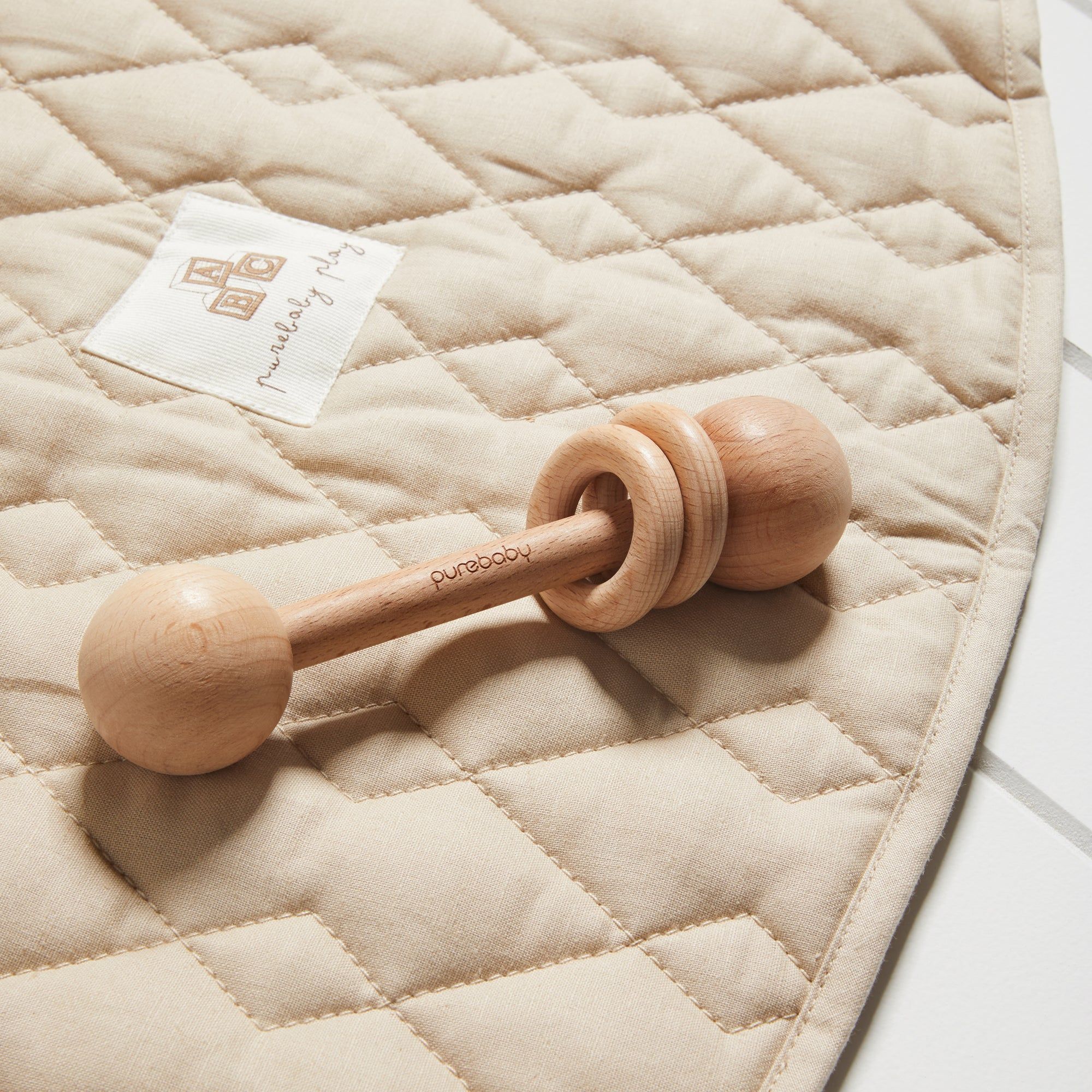Wooden rattle laying on play mat