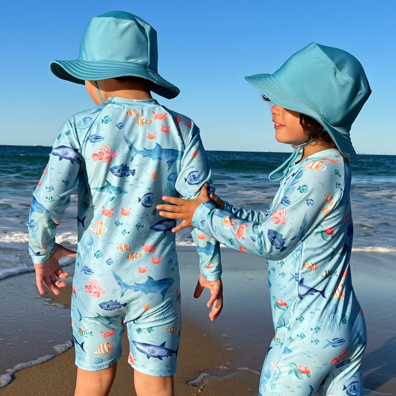 Children in swimwear and hats at beach