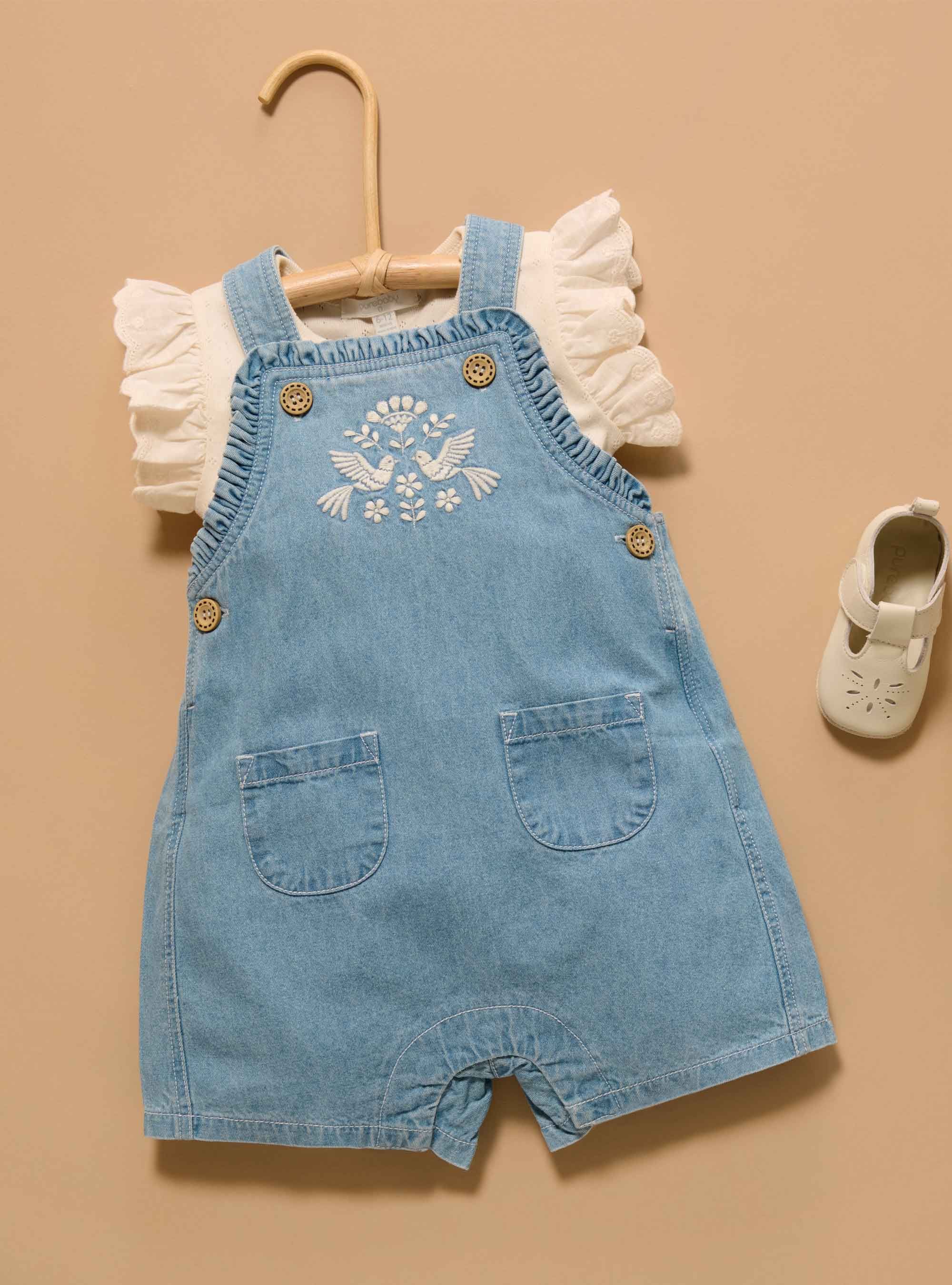 Flatlay of denim overalls layered over a white tee with ruffle sleeves
