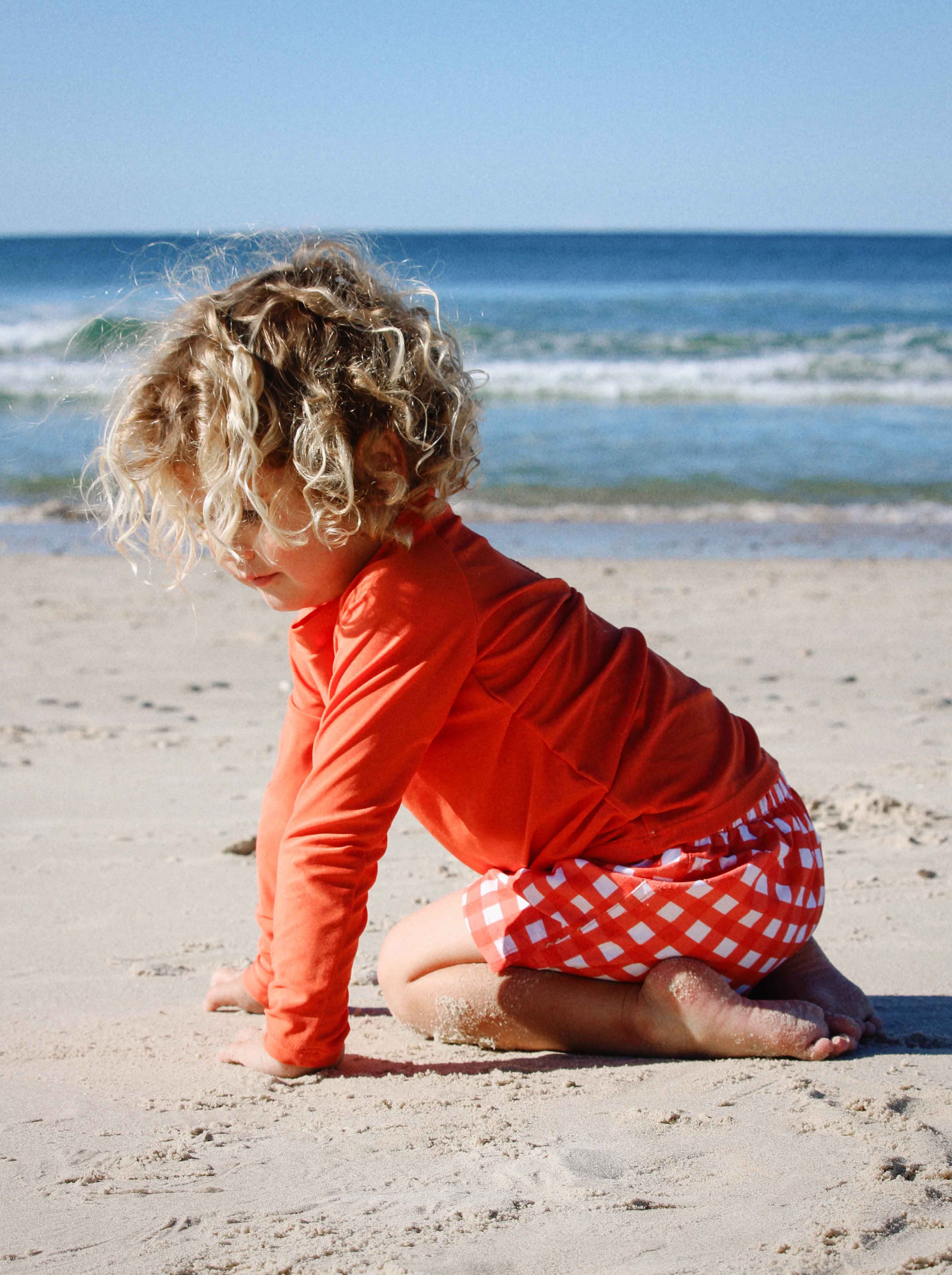 Child playing in the sand wearing Purebaby rashie and swim shorts set