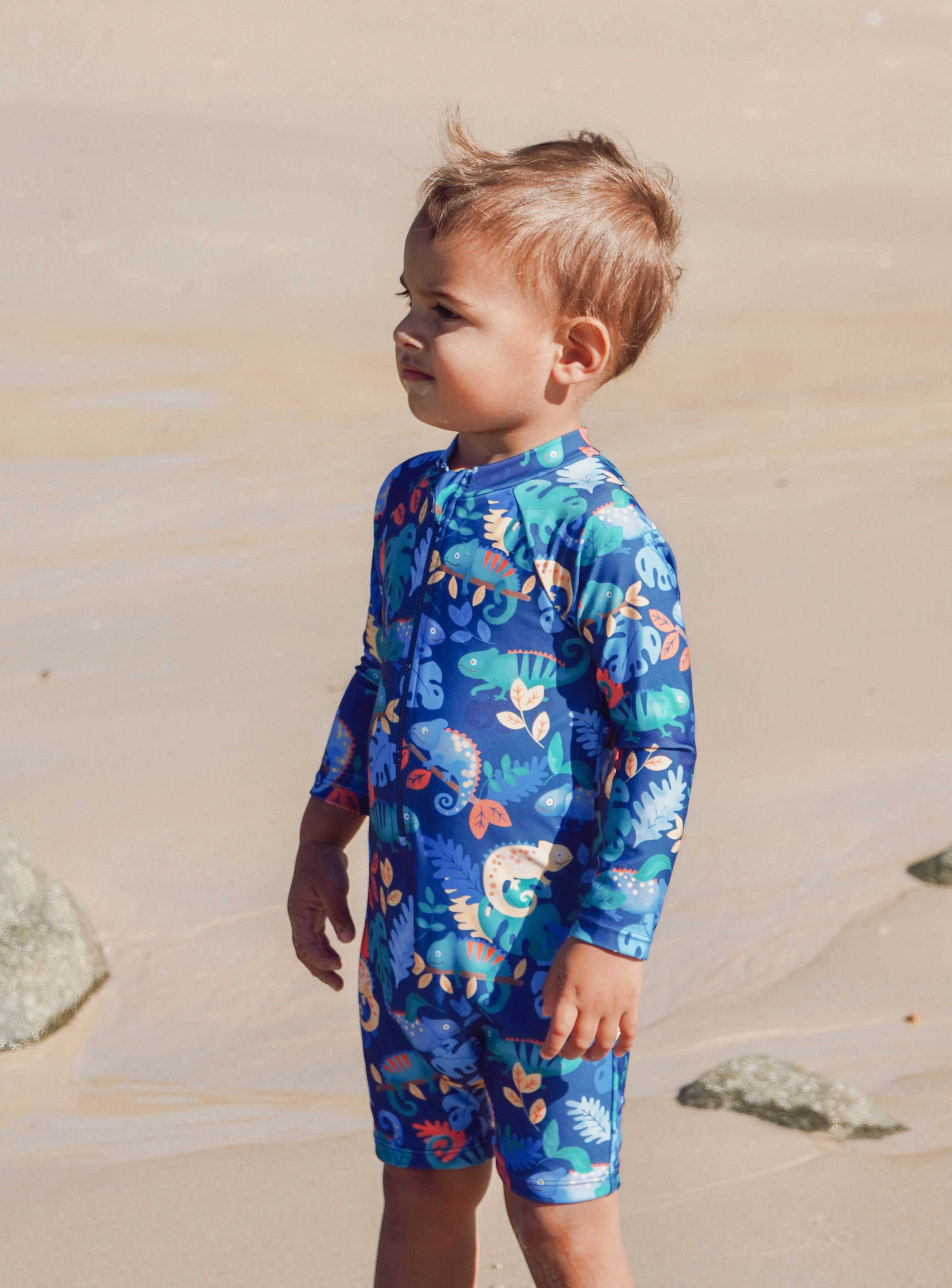 Toddler wearing Purebaby long sleeve swimsuit at the beach for sun protection.