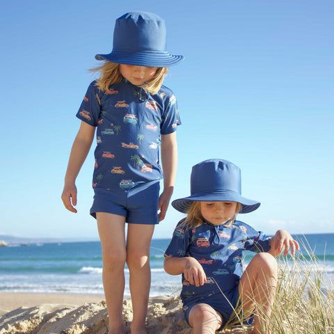 2 boys at the beach wearing blue Purebaby swimwear 