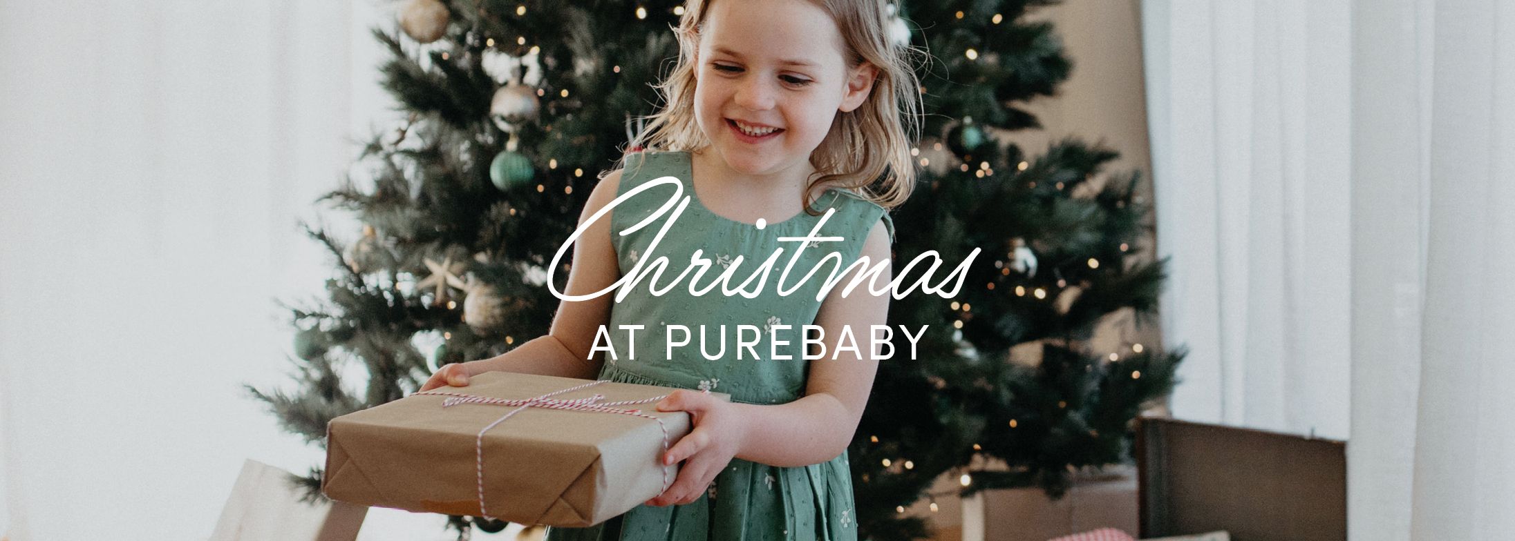 child wearing a kids Christmas dress holding a present