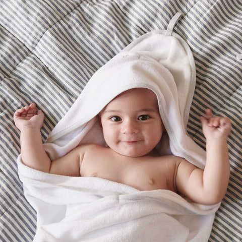 Baby laying on blanket wrapped in Purebaby hooded towel