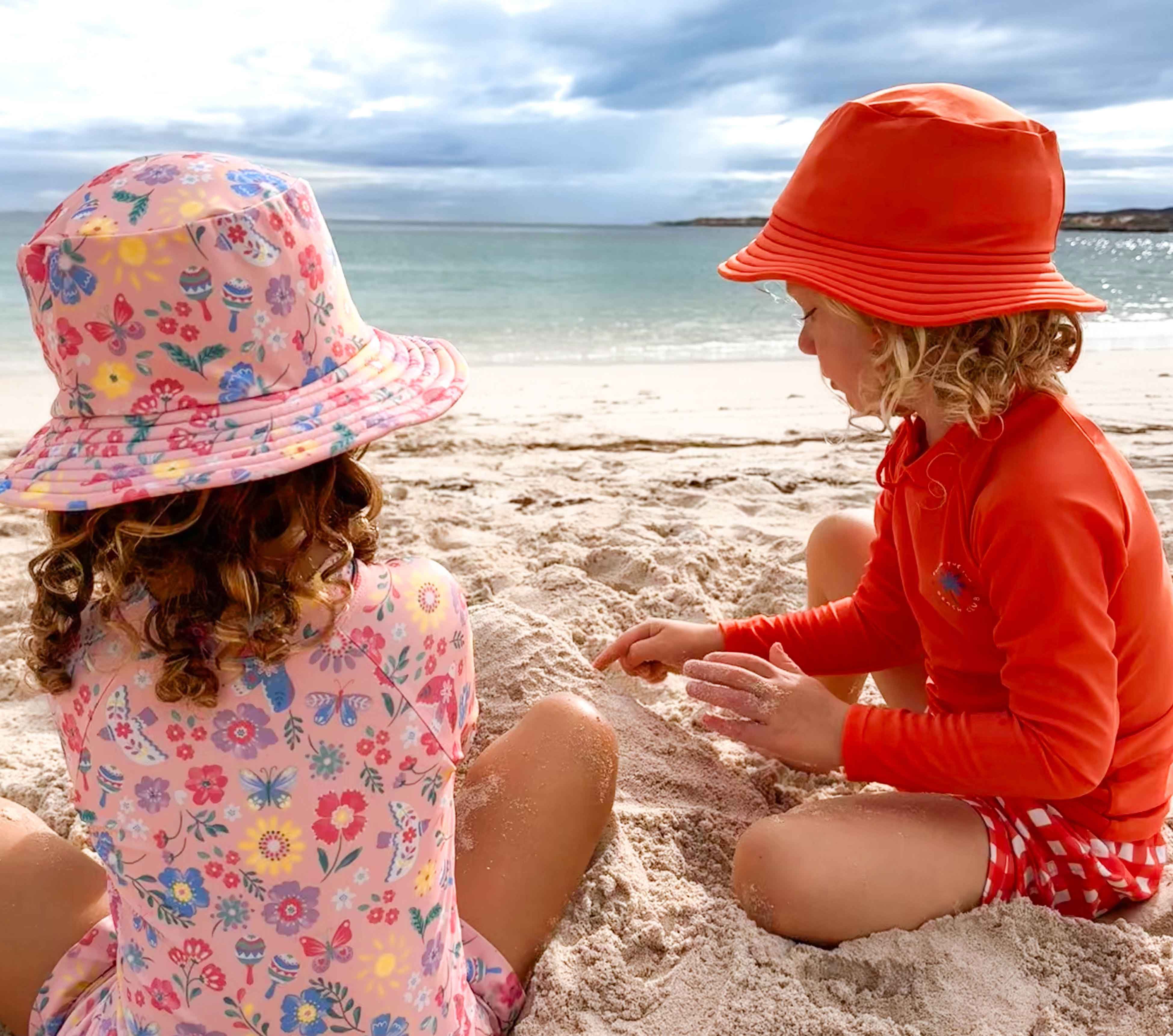 Kids playing at the beach wearing wide brim bucket sun hat