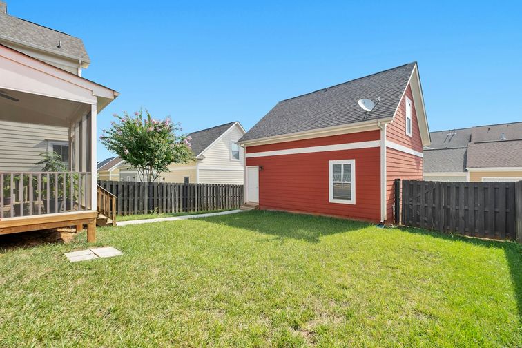 Bright red backyard rental unit behind a main home on a green lawn — lendsimpl guide to rental income mortgage qualification in Canada