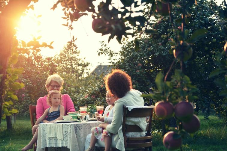 Two women and two children sitting outside a bright suburban house in daylight — lendsimpl guide to financing a multigenerational home in Canada