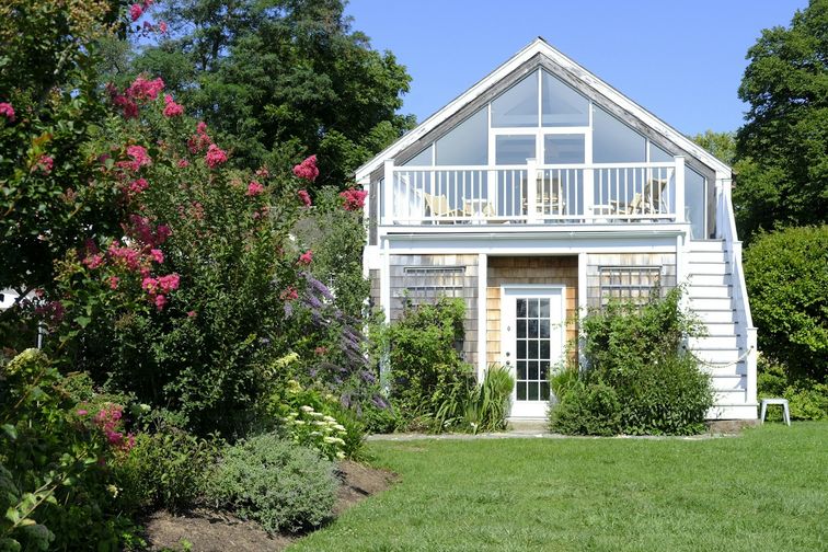 Bright two-storey backyard garden suite with a flowering garden — lendsimpl guide to secondary suite financing in Ontario