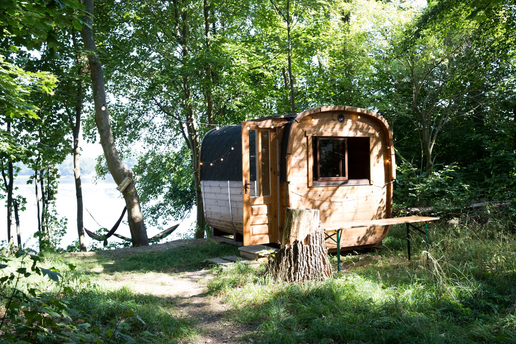 Holzsauna in Fassform zwischen Bäumen auf dem Gelände von Neupitz