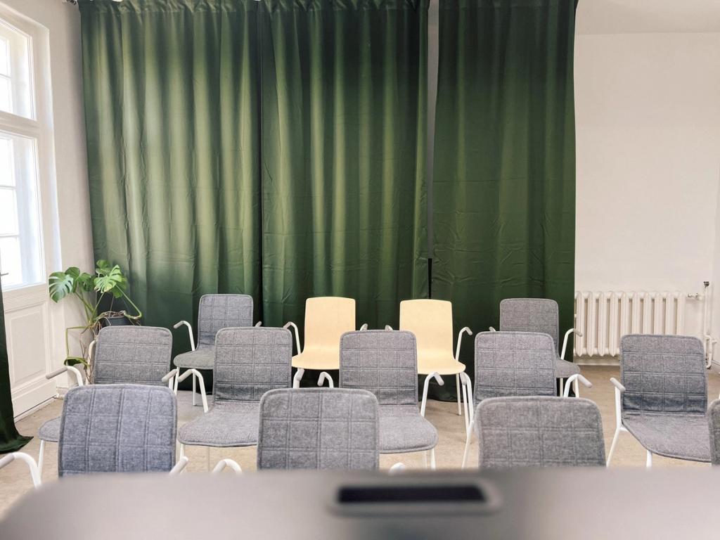 Stuhlkreis vor grünen Vorhängen im Workshopraum Seeblick, Setup für Gesprächsrunden beim Offsite
