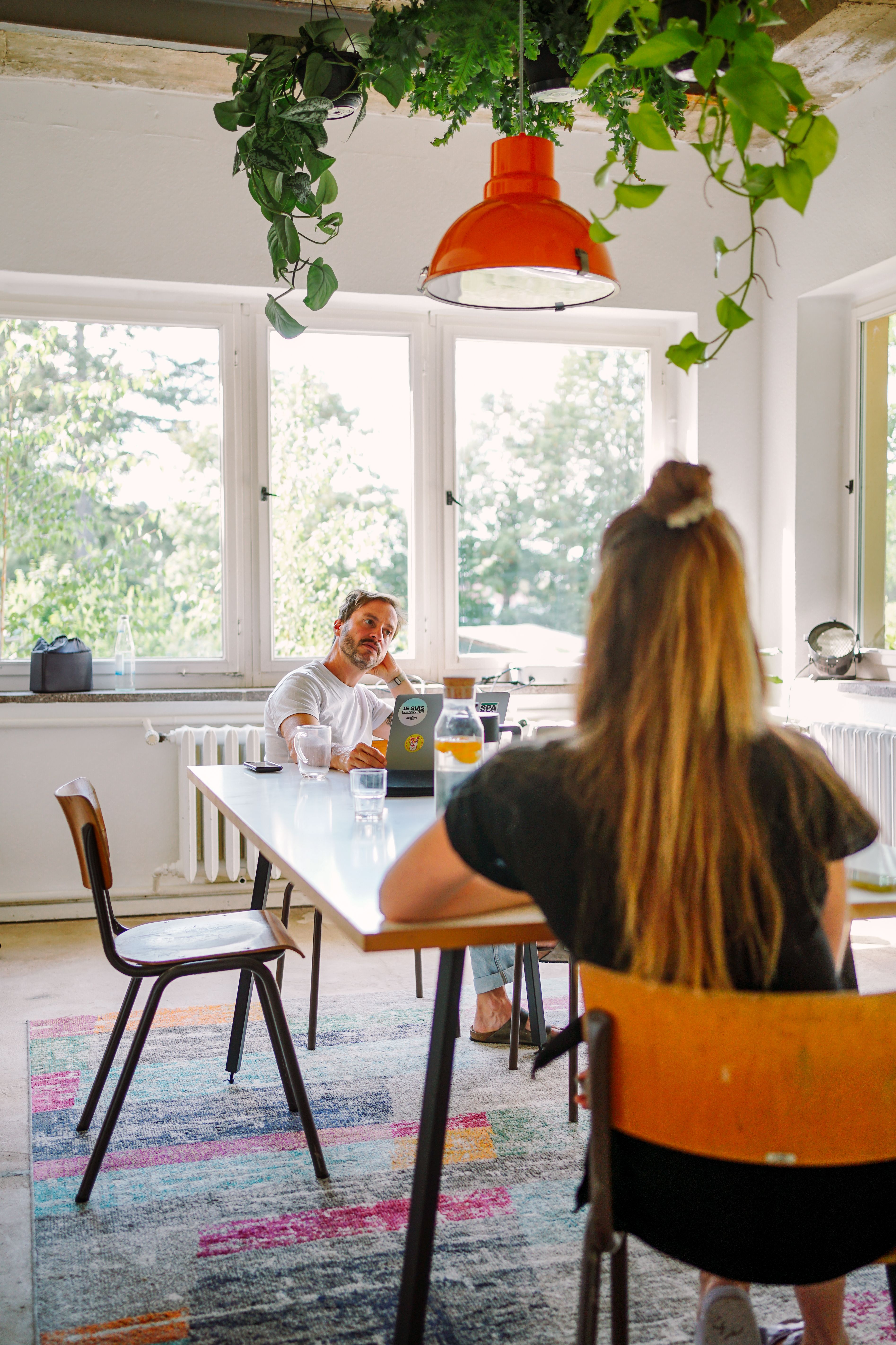 Zwei Personen sitzen am Tisch im Wintergarten und unterhalten sich während einer Break-Out Session mit ernstem Blick.