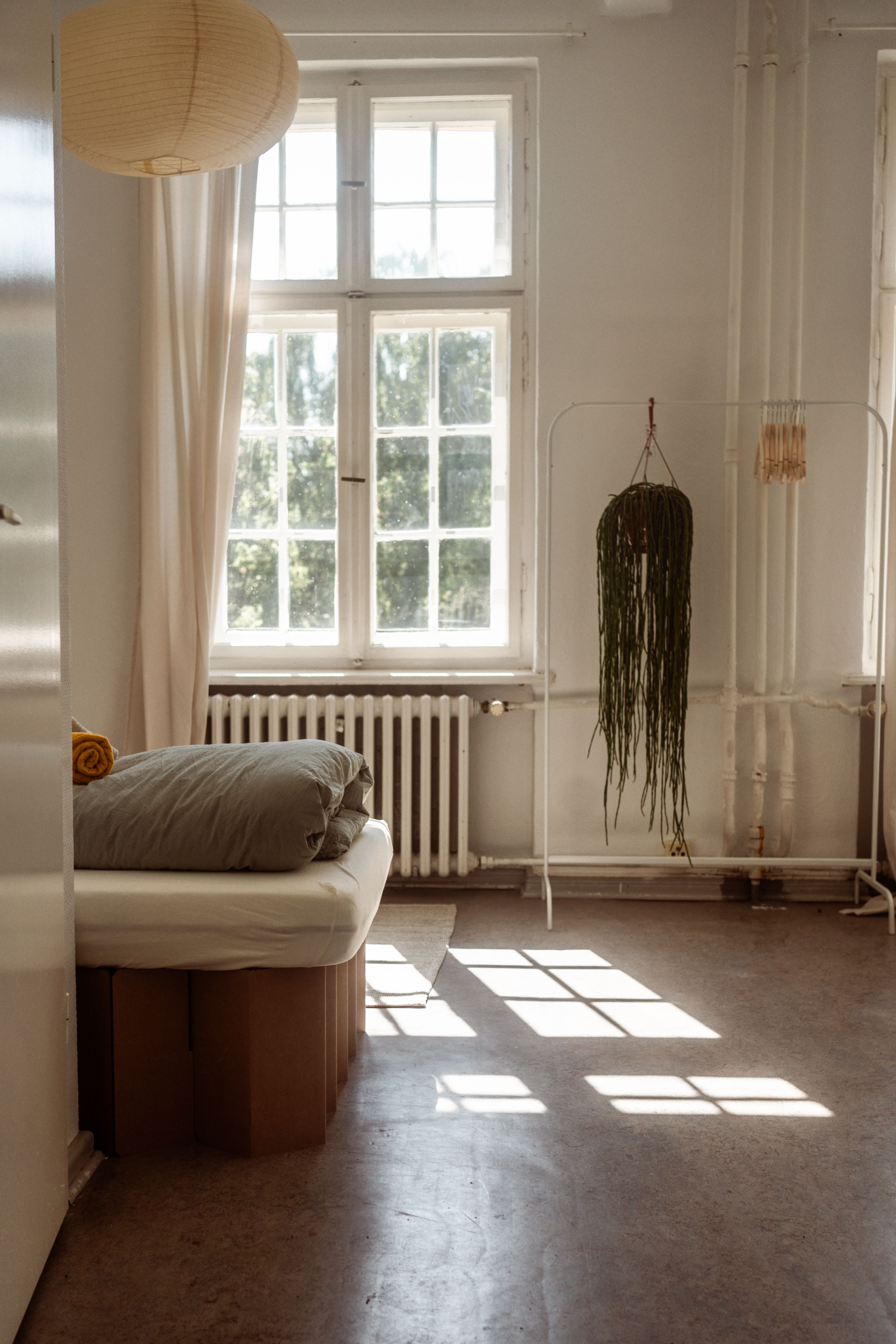 Schlichtes Zimmer in der Villa mit hohem Sprossenfenster und Bett, Gruppenunterkunft für Team-Retreats