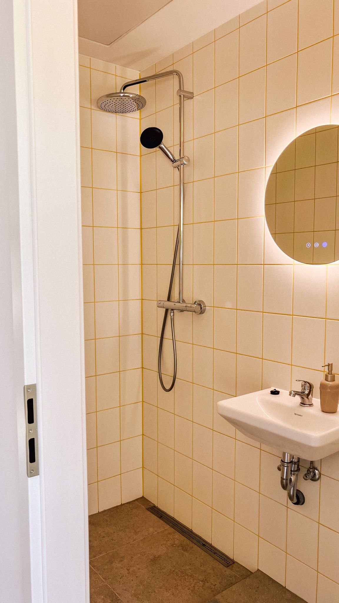 Bad im Bungalow mit Dusche, rundem Spiegel und Waschbecken