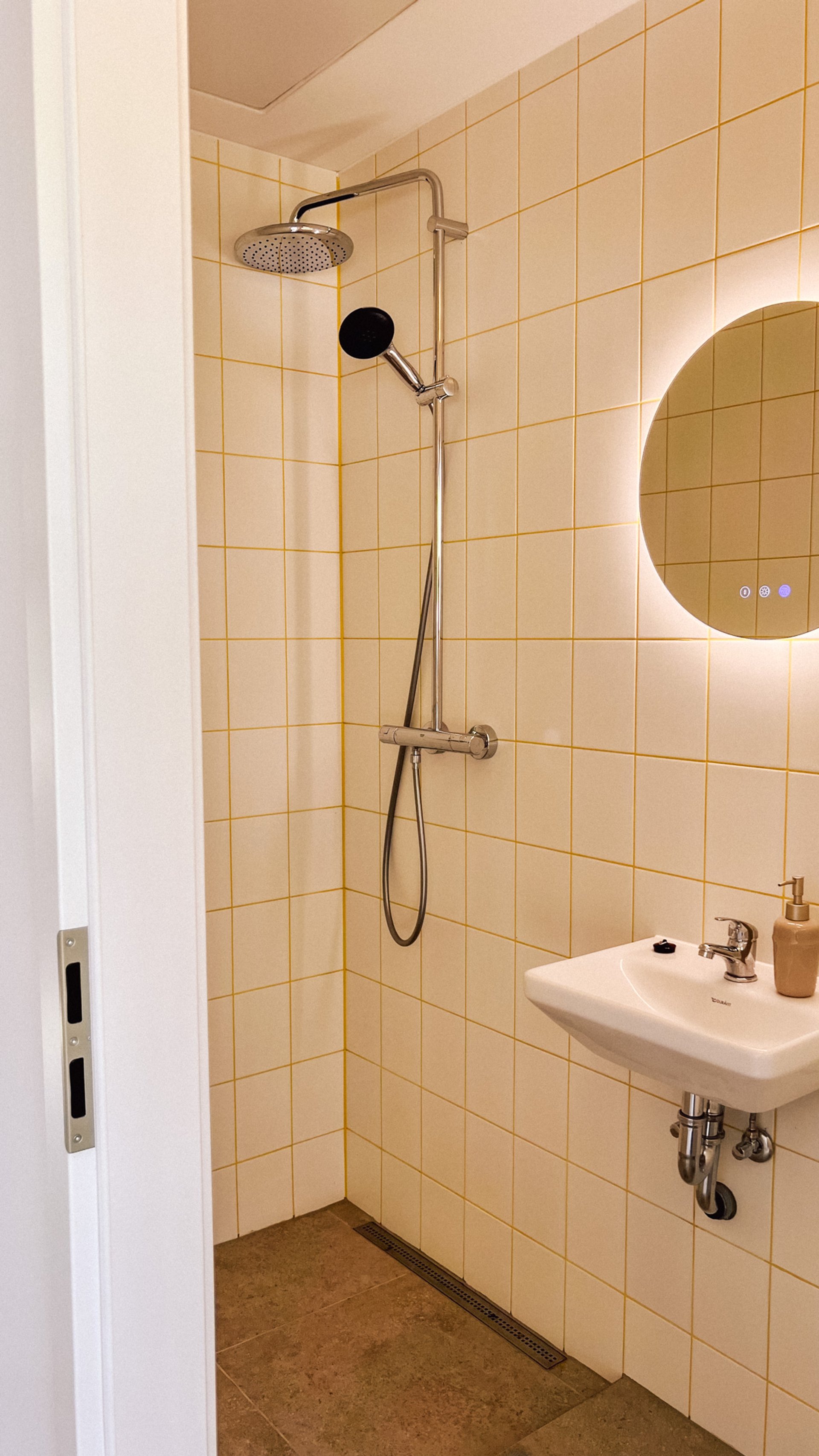 Bad im Bungalow mit Dusche, rundem Spiegel und Waschbecken