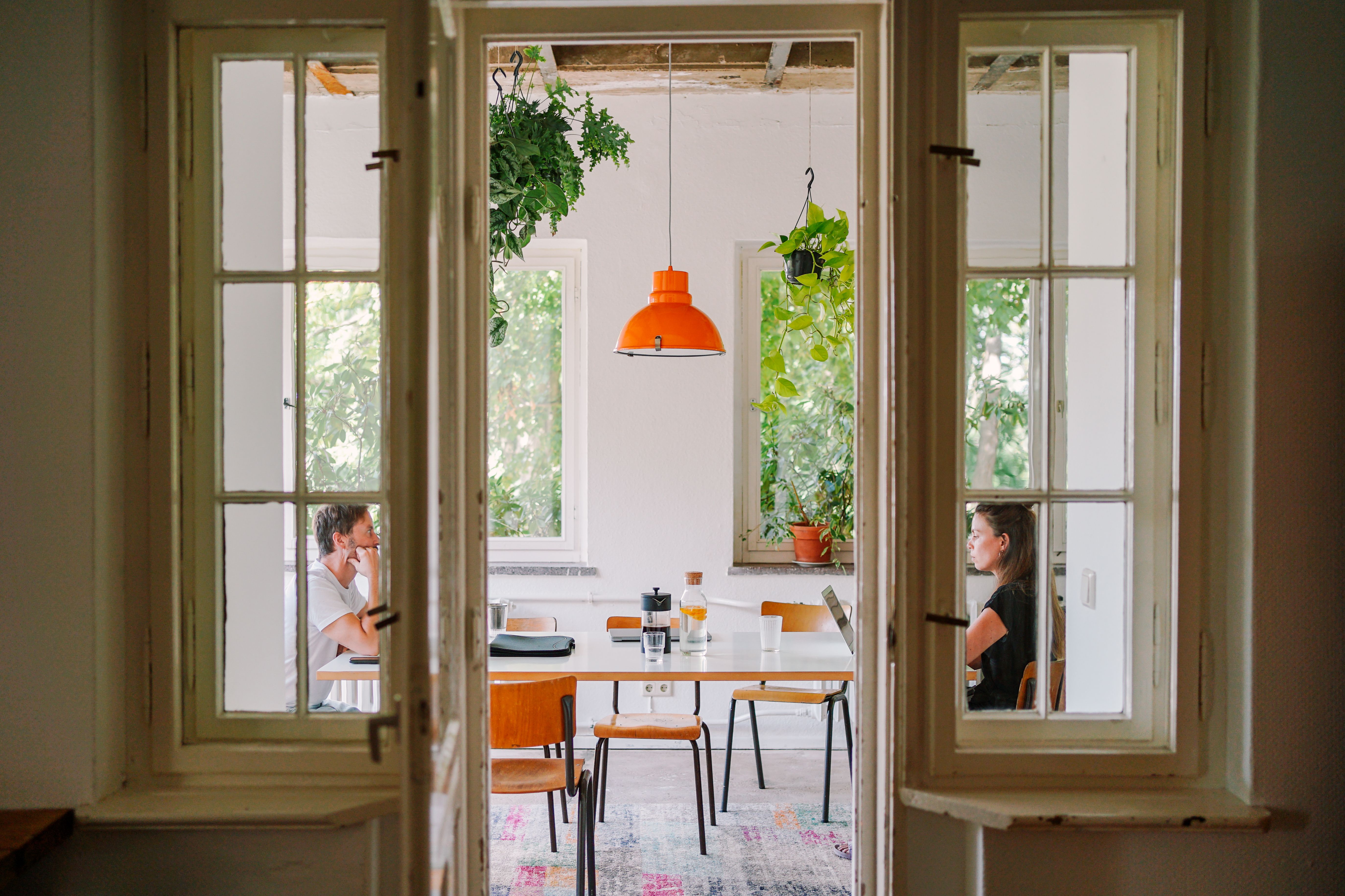 Blick durch geöffnete Flügeltüren in den Wintergarten der Villa Neupitz mit Tisch und Pflanzen