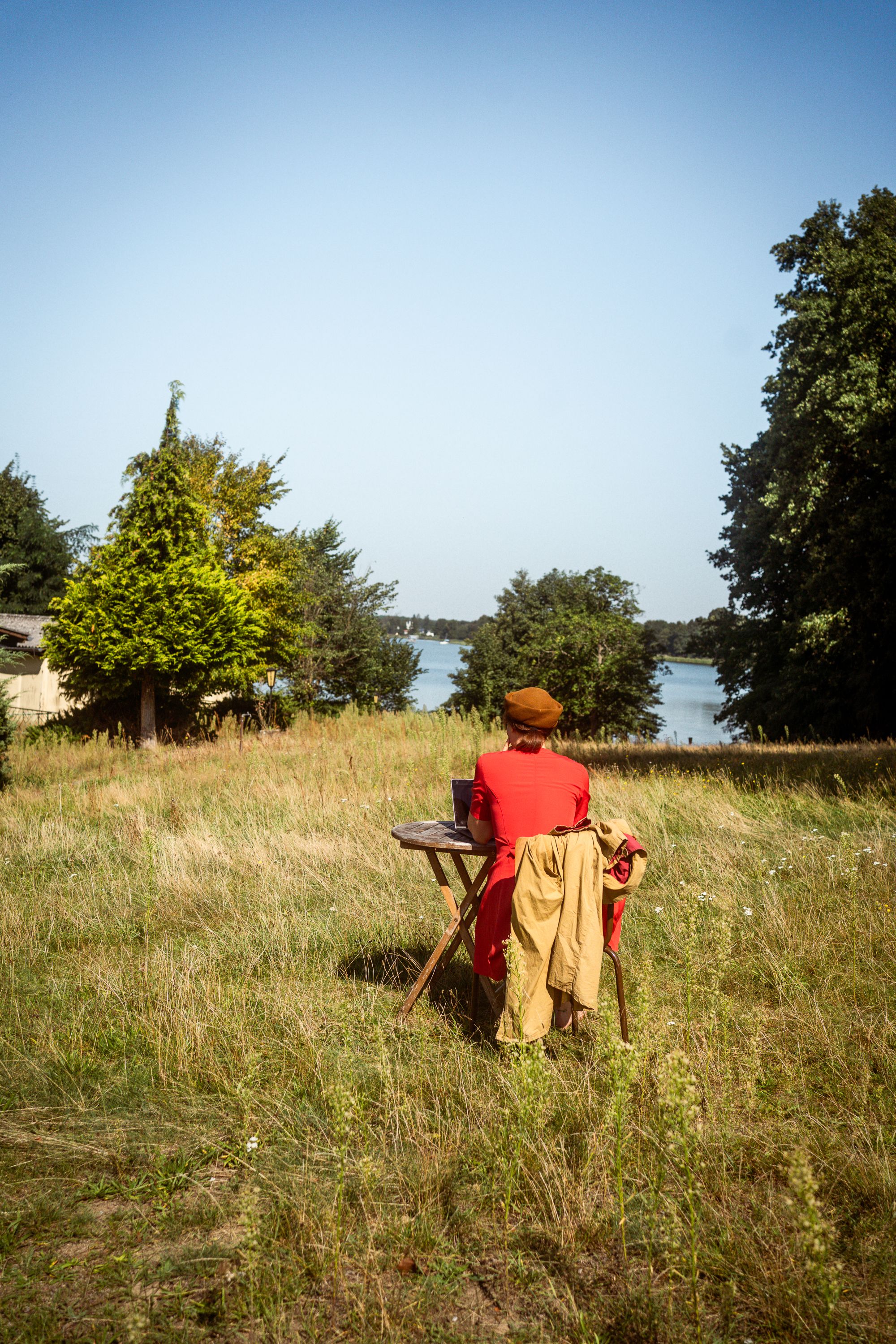 Person arbeitet bei ihrer Workation in Neupitz auf einem Stuhl mitten auf der Wiese mit Seeblick