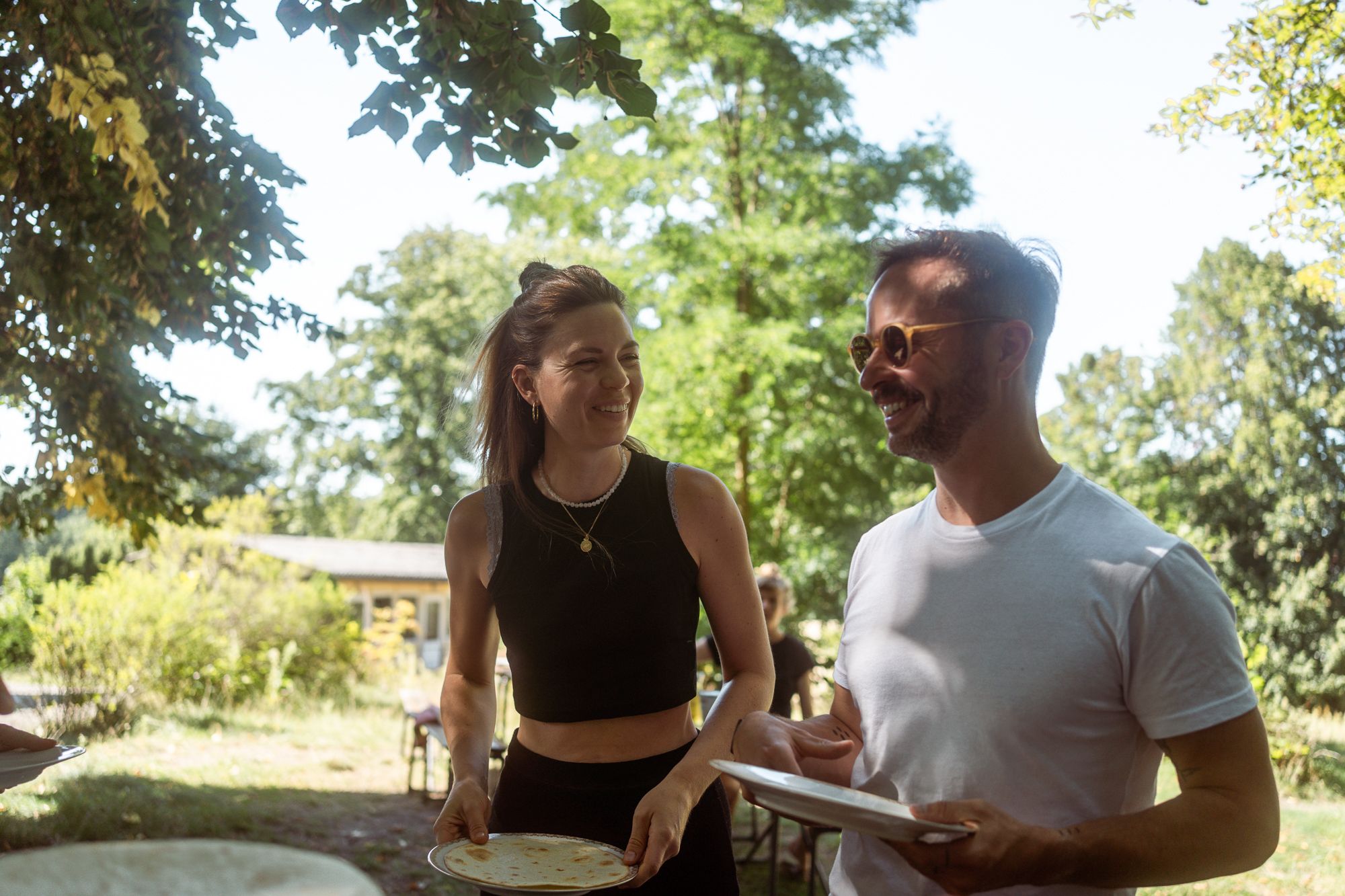 Zwei Gäste unterhalten sich lachend mit Tellern beim Essen im Freien während eines Team-Retreats