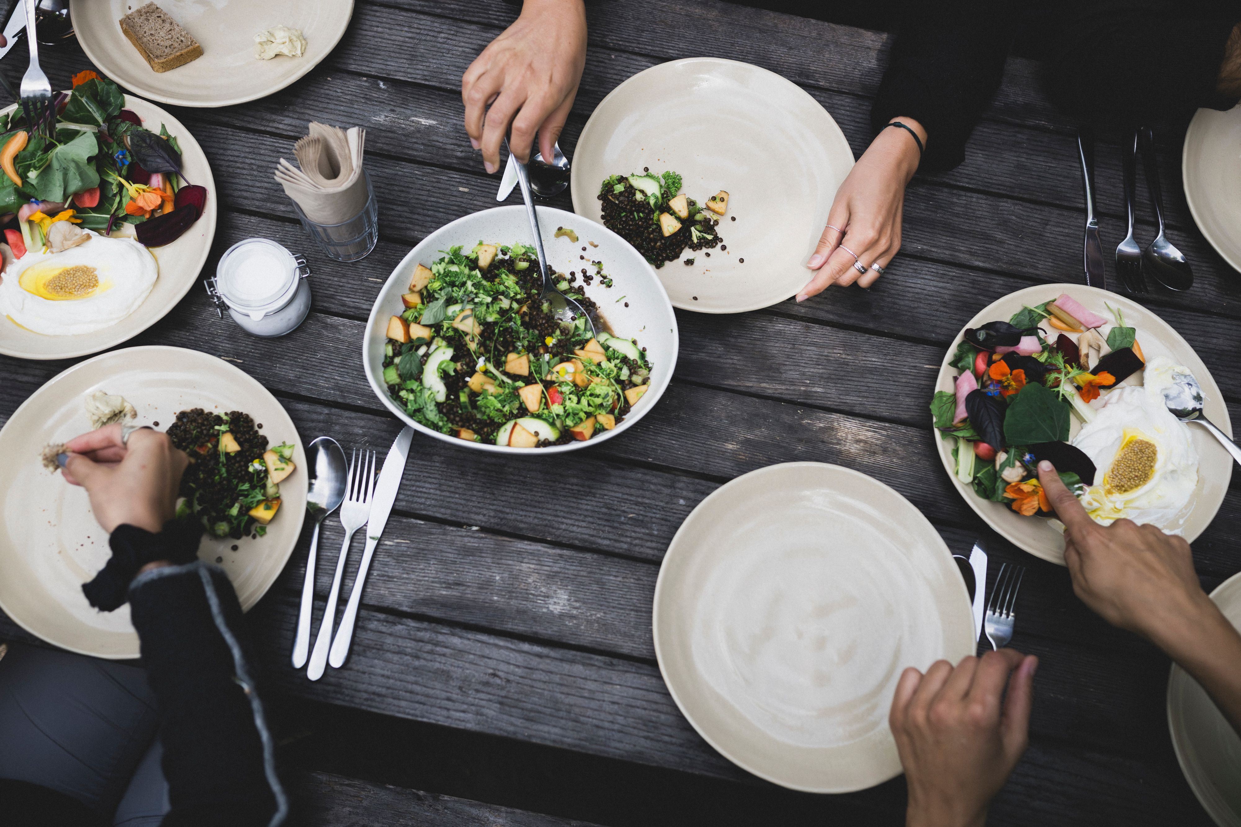 Offsite-Gruppe bedient sich am Holztisch an frischen vegetarischen Gerichten zum Teilen