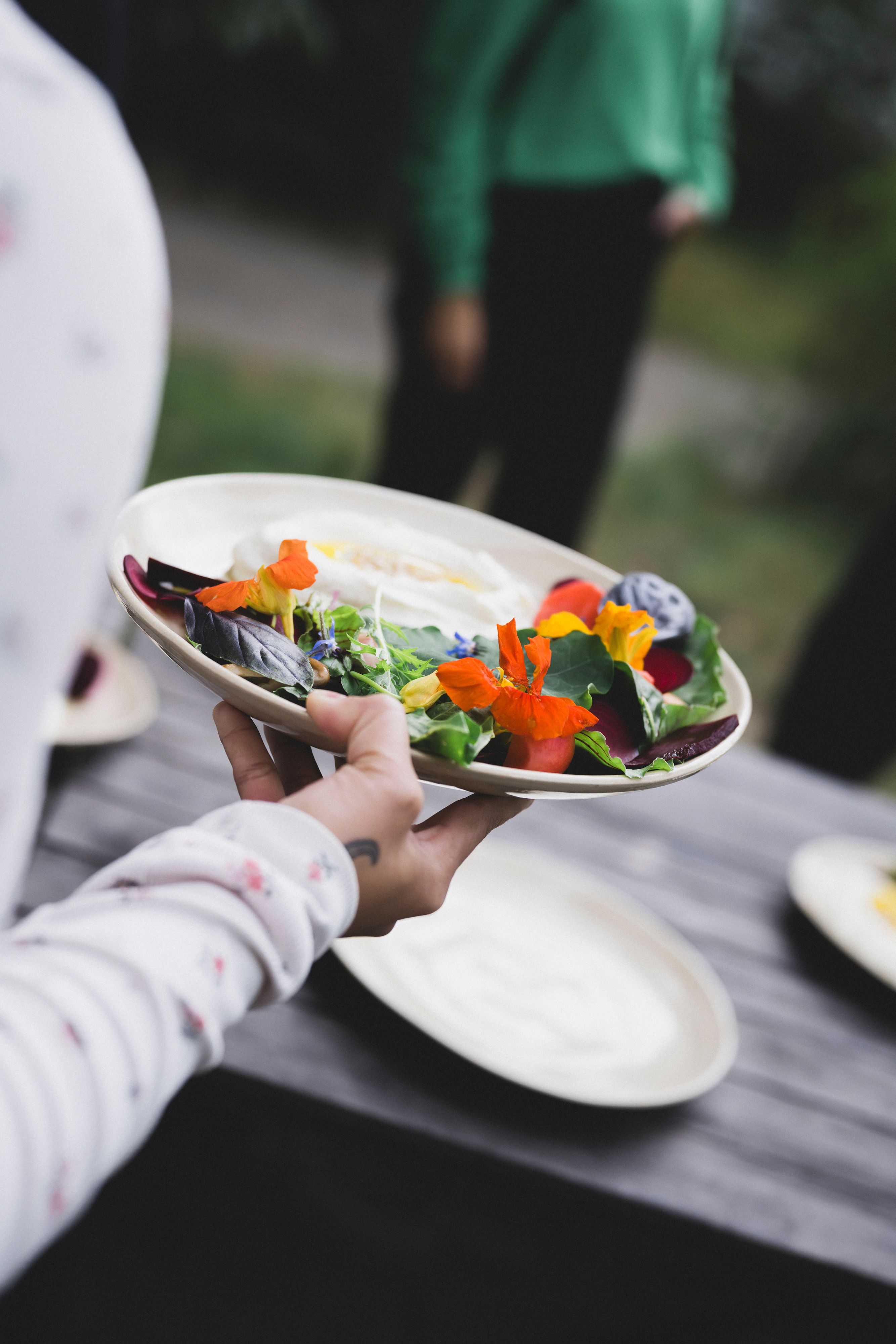 Person von Neupitz serviert eine vegetarische Vorspeise mit regionalem Frischkäse und frischem Gemüse