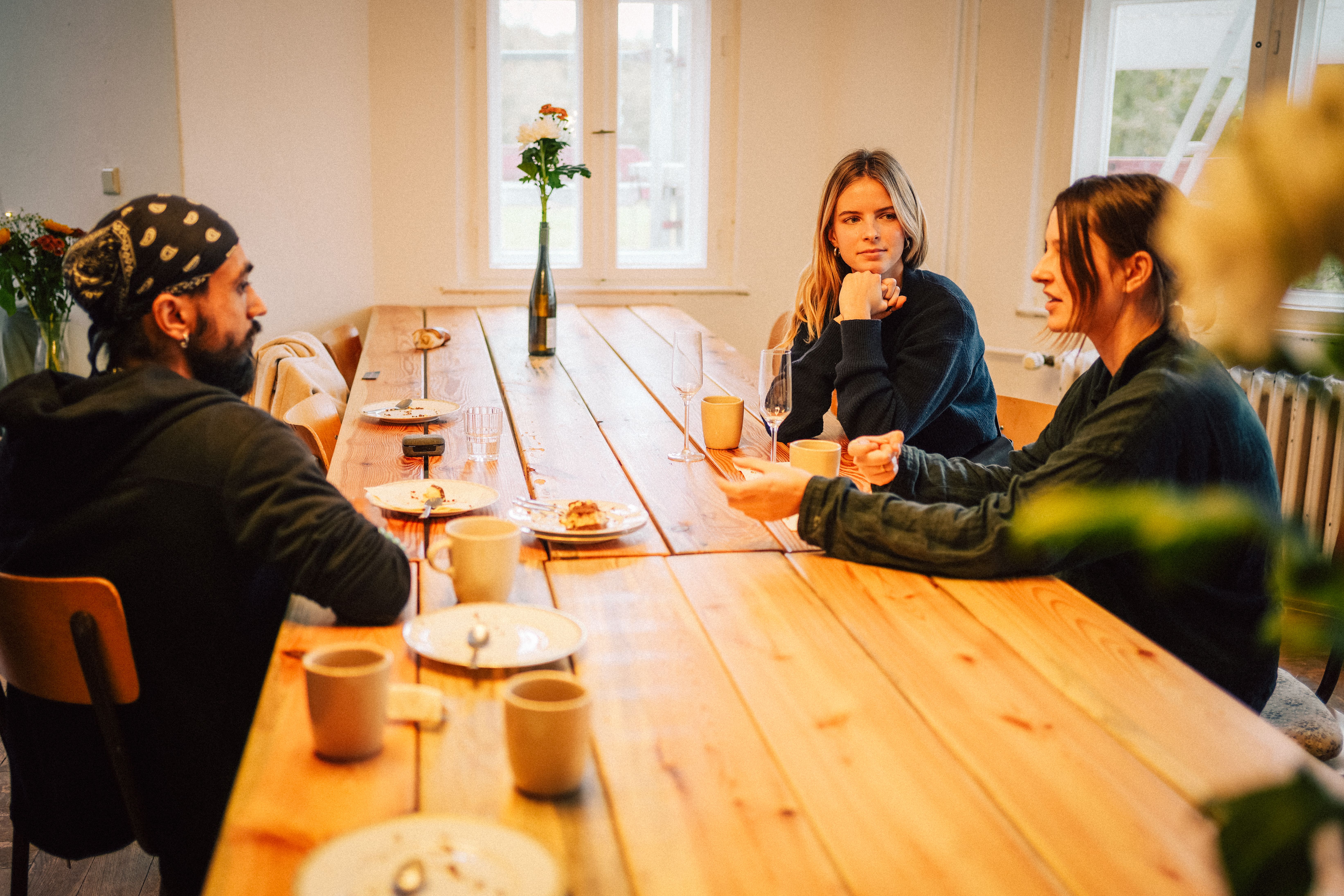 Gruppe im Gespräch bei Kaffee an der langen Holztafel im Kleinen Saal