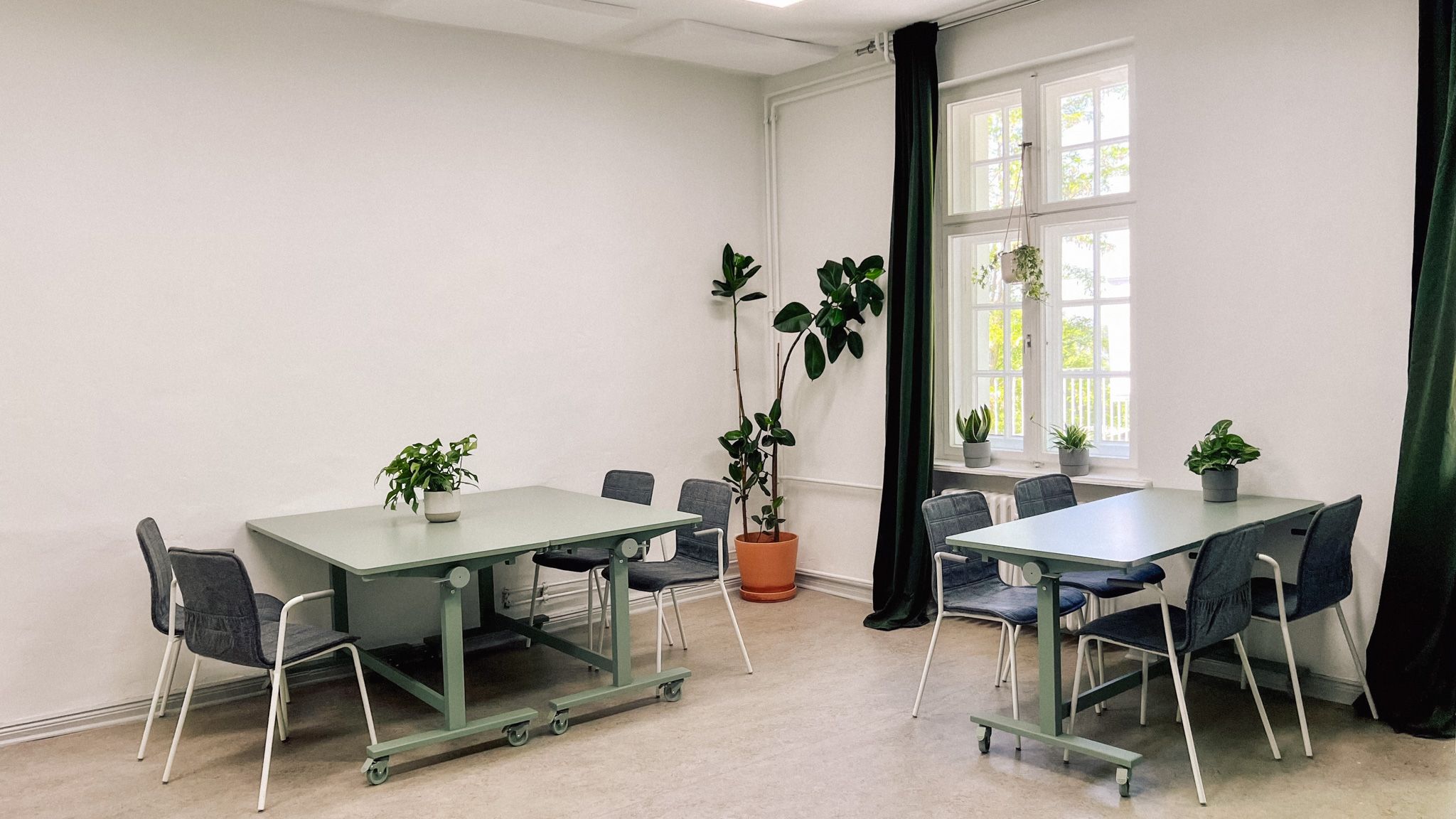 Zwei Gruppentische mit Stühlen und Pflanzen im Workshopraum Seeblick, Setup für Kleingruppenarbeit