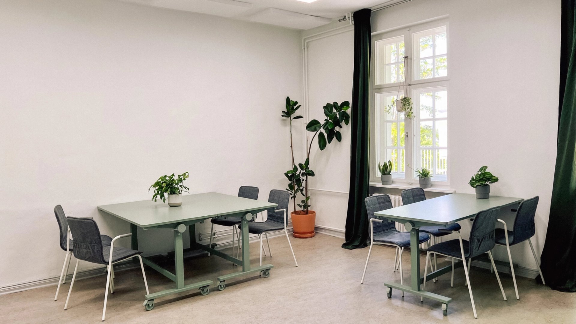 Zwei Gruppentische mit Stühlen und Pflanzen im Workshopraum Seeblick, Setup für Kleingruppenarbeit