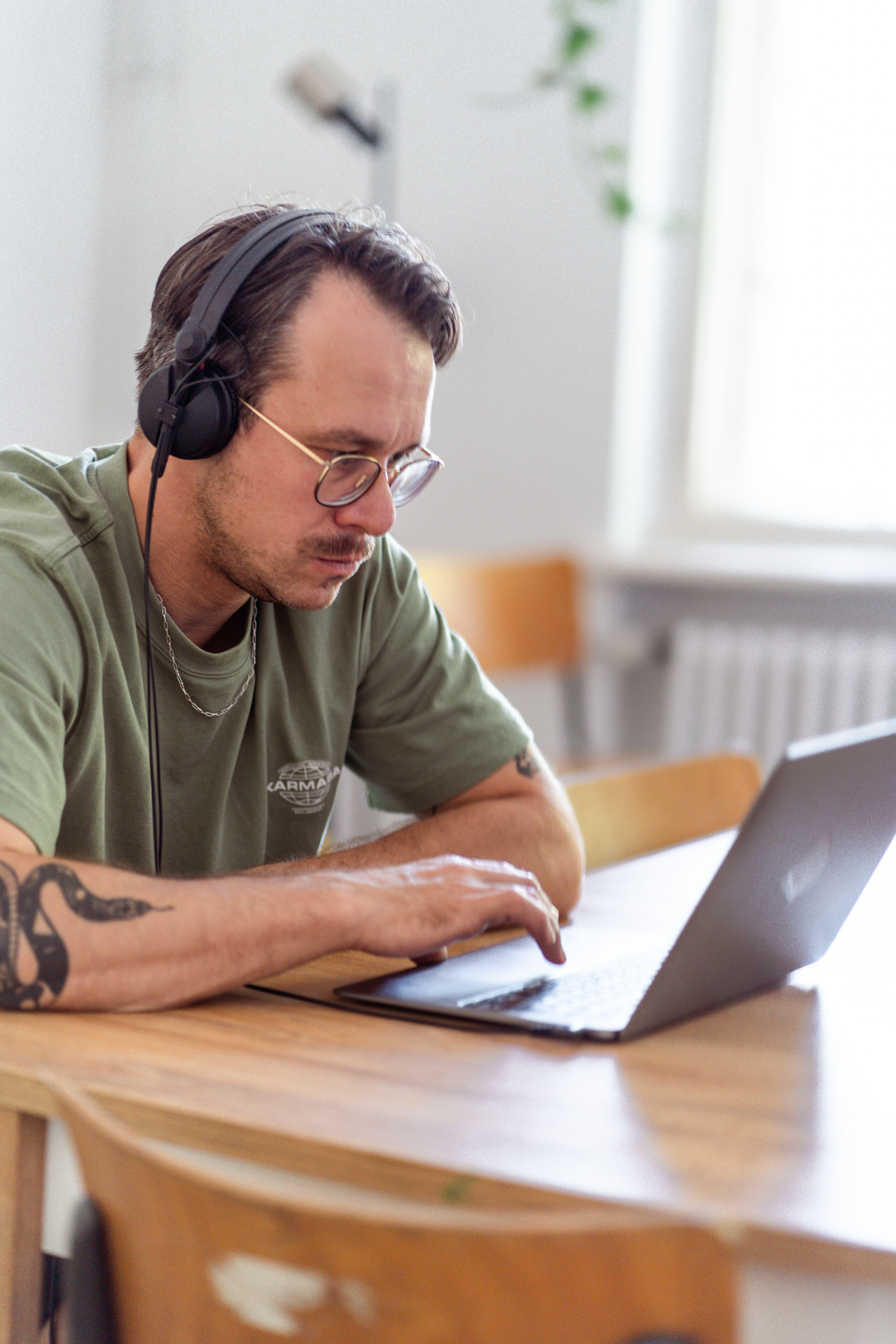 Person mit Kopfhörern arbeitet am Laptop im hellen Coworking-Bereich in Neupitz