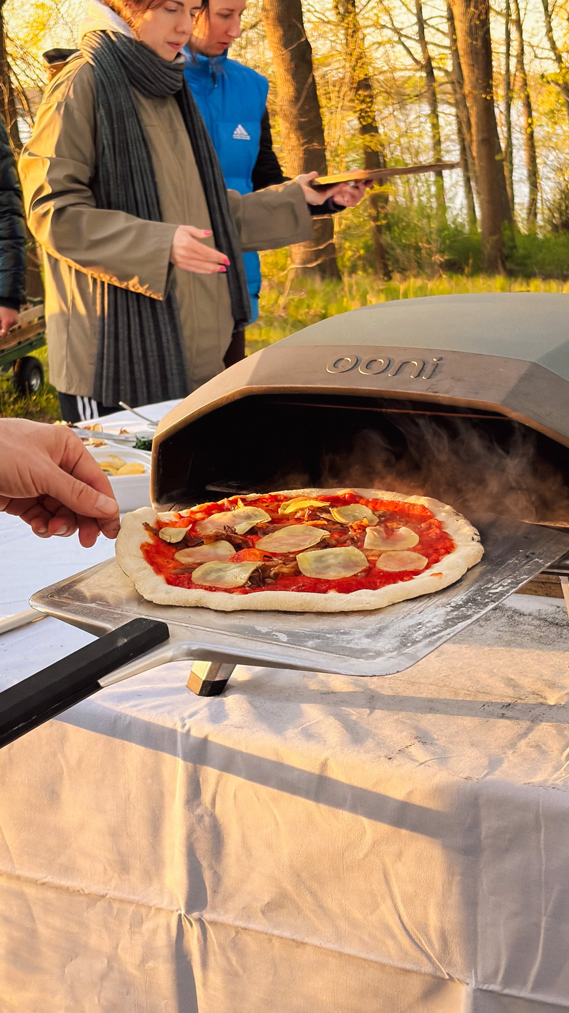 Frisch belegte Pizza wird in den Pizzaofen geschoben, Pizza-Abend beim Teamevent