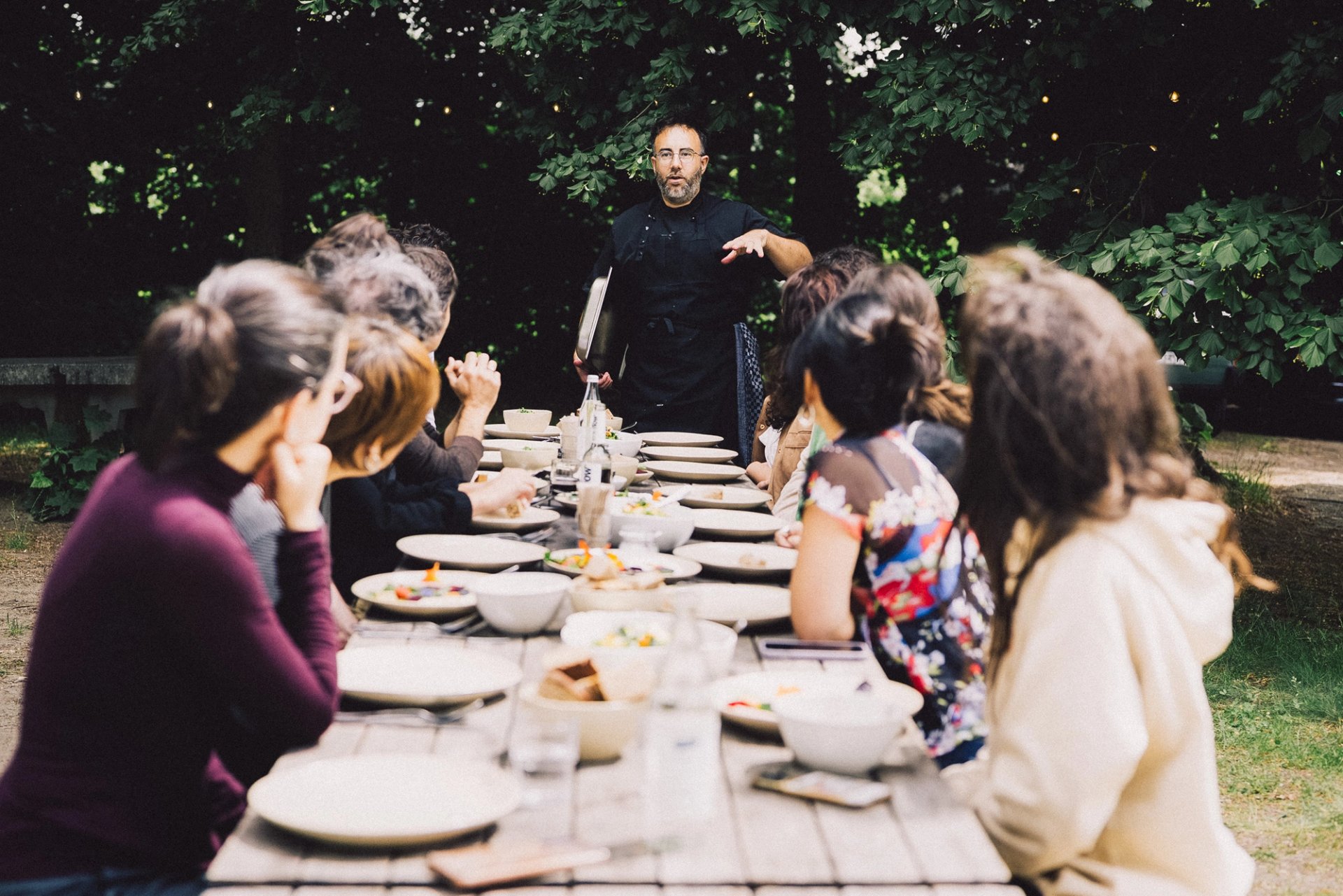 Team-Retreat in Neupitz: Gruppe an langer Tafel im Freien, ein Mann spricht am Kopfende