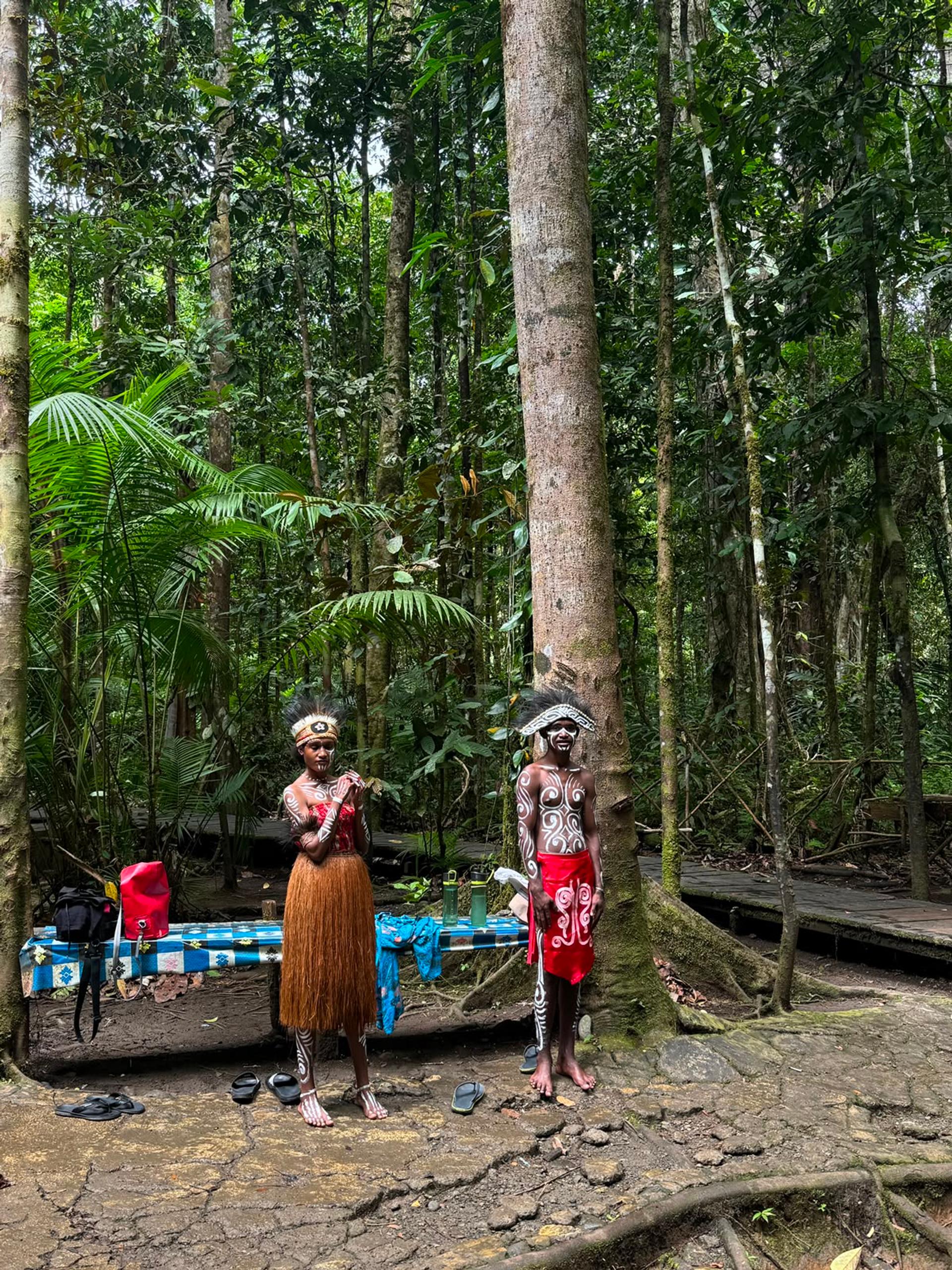 Two people in traditional dress and body paint at blue river