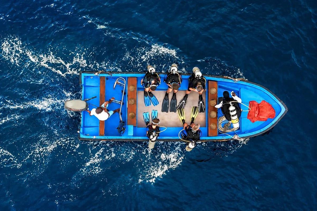 Aerial view of divers in wetsuits preparing their gear on the dive deck of the Mari phinisi