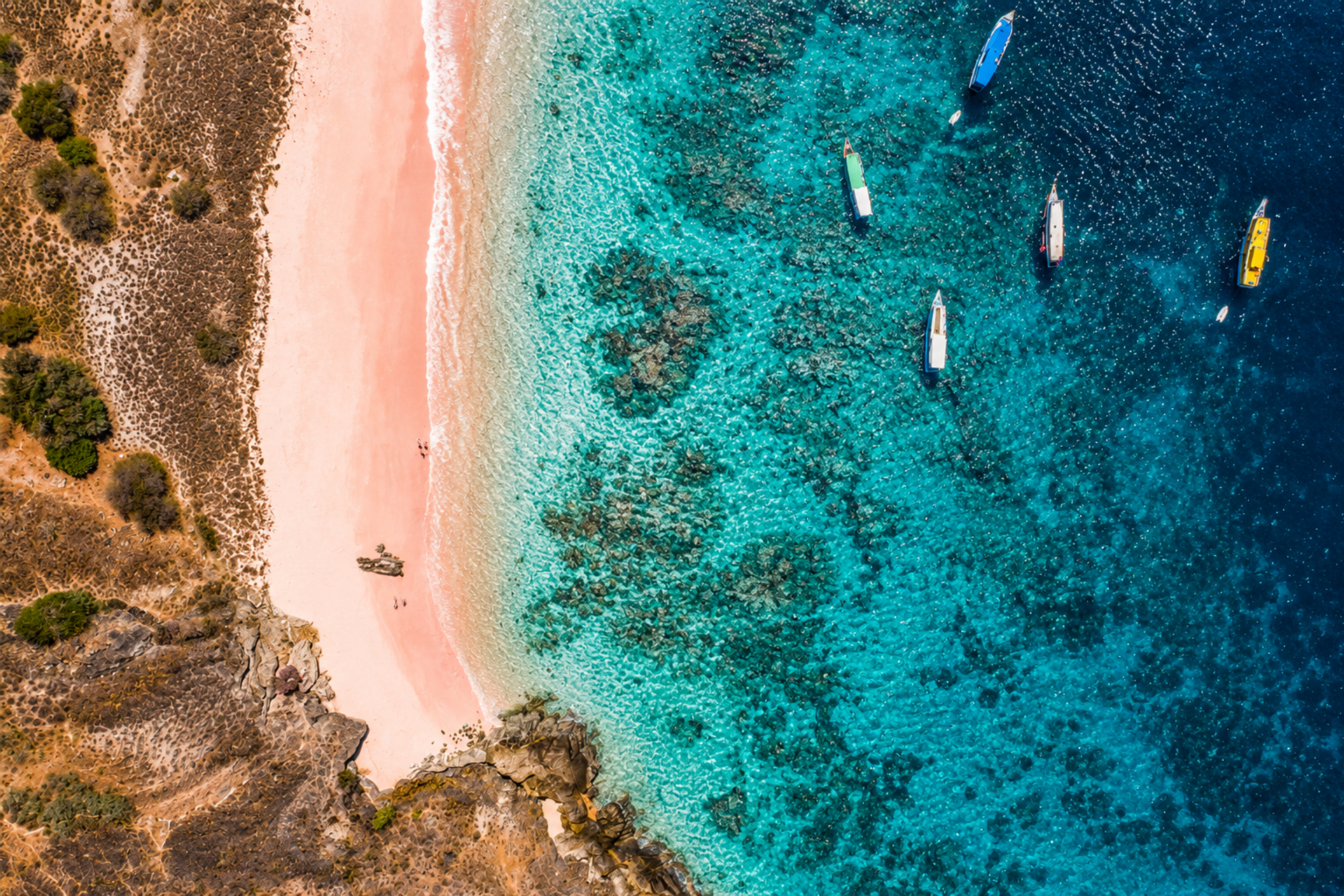 Pink-tinged sand meeting turquoise shallows at Pantai Merah