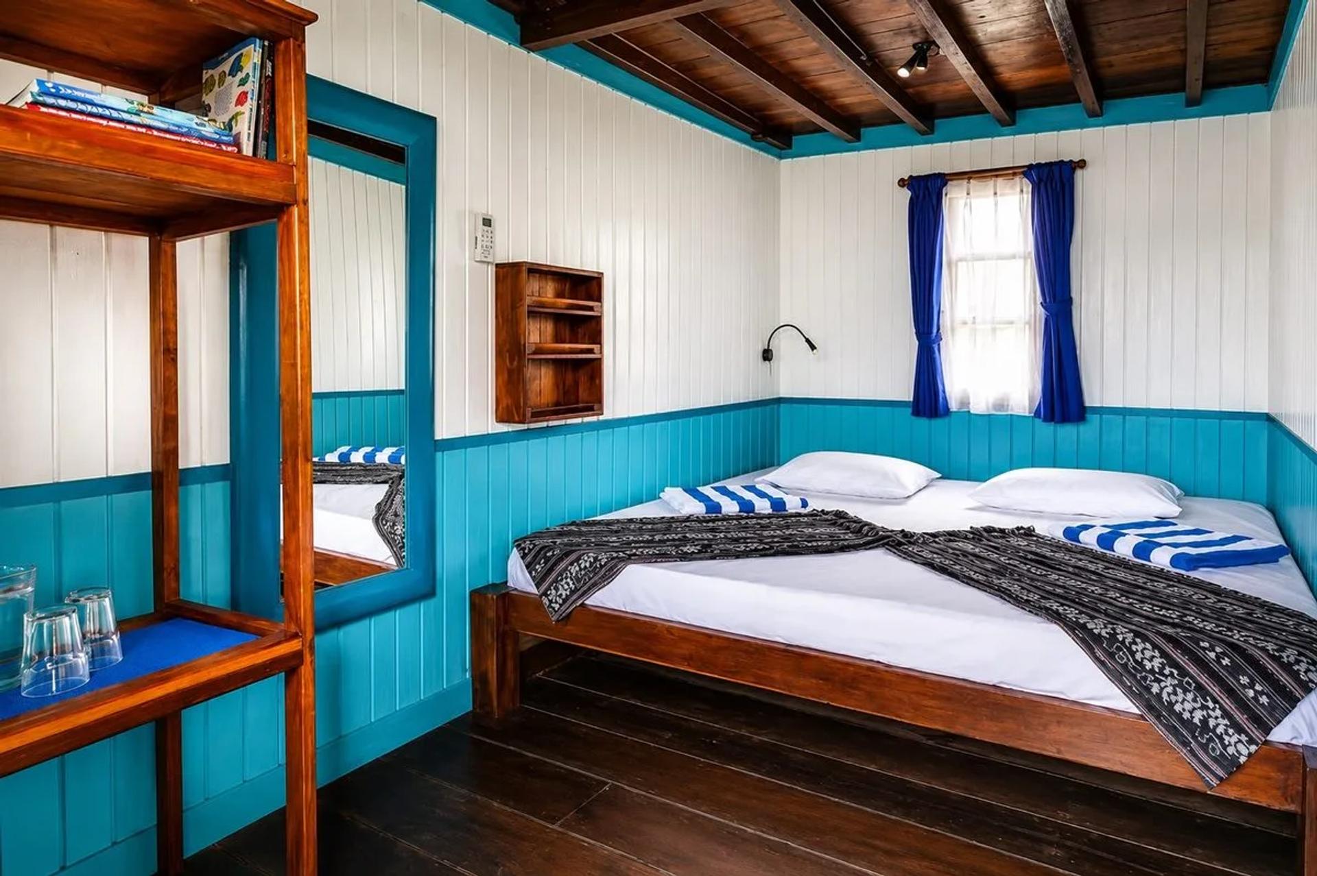 Guest cabin with a made bed beside a curtained window