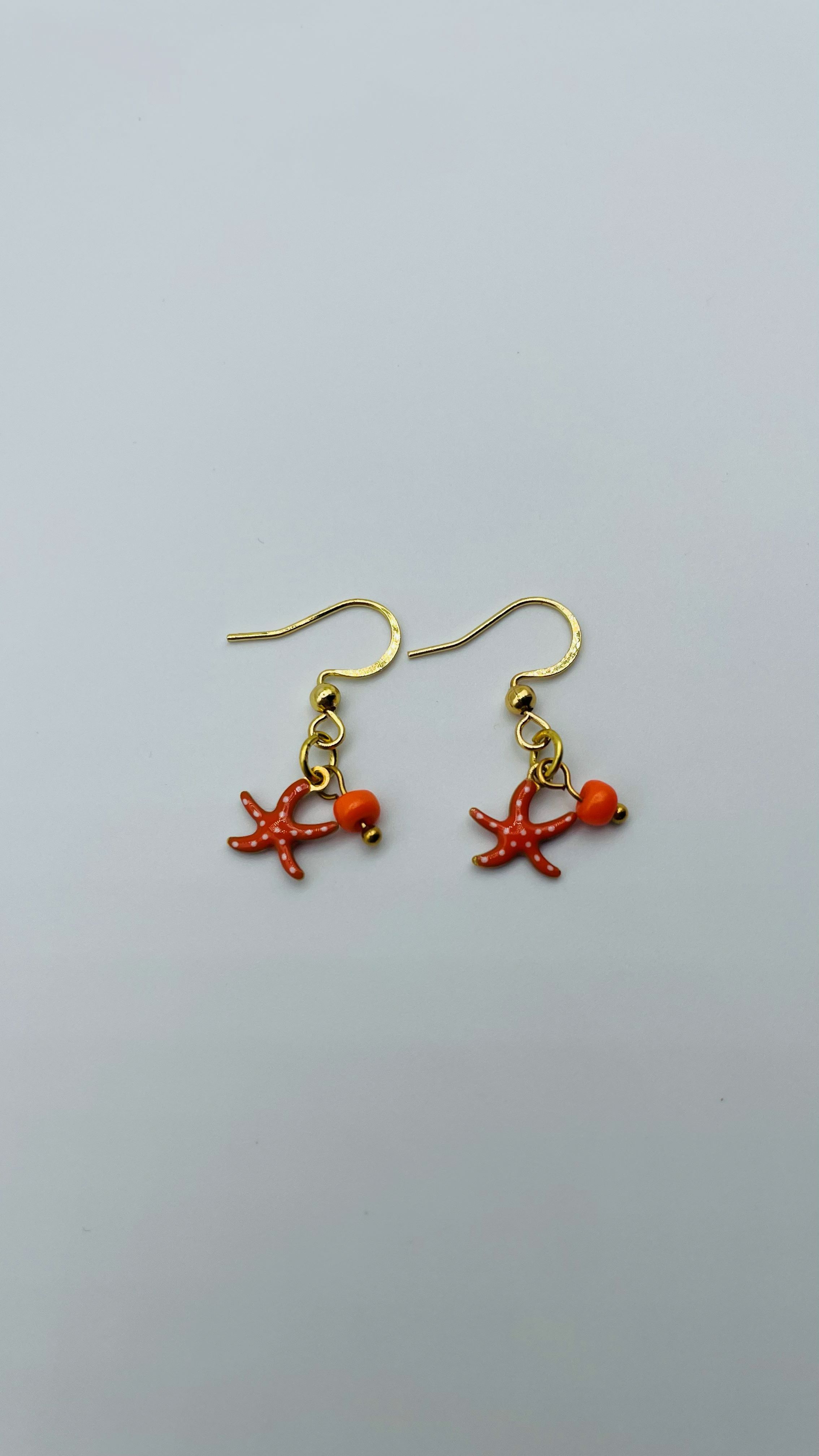 Gouden oorbellen met oranje zeester met stippen