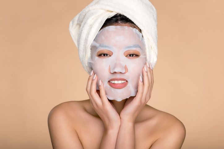 A young woman with a sheet face mask applied to her face