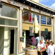 Burgers and Barrels in Bath: Vibrant front view with people enjoying outdoor seating, savouring delicious burgers and drinks in a lively atmosphere