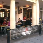 The Oven in Bath: Front view with patrons enjoying outdoor dining, savouring delicious food in a vibrant atmosphere at this popular restaurant