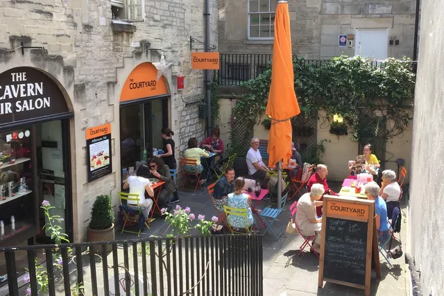 The Courtyard Cafe in Bath: Lively front view with patrons savouring food and drinks in the inviting outdoor seating area