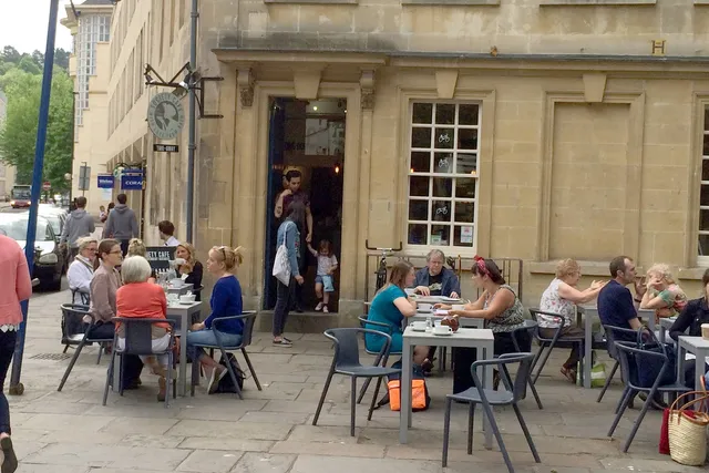 Society Cafe in Bath: Front view with people savouring the outdoor seating area, creating a vibrant atmosphere at this popular coffee spot