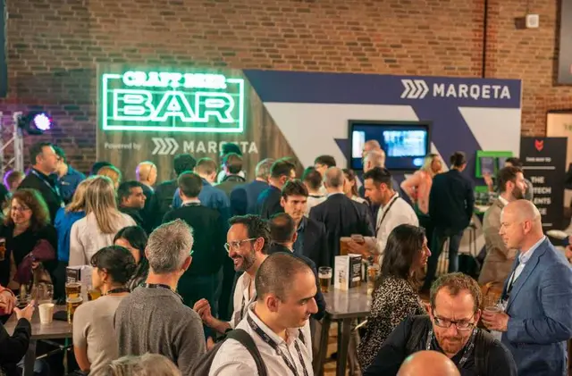 People socializing at an event with a 'Craft Beer Bar' sponsored by Marqeta.